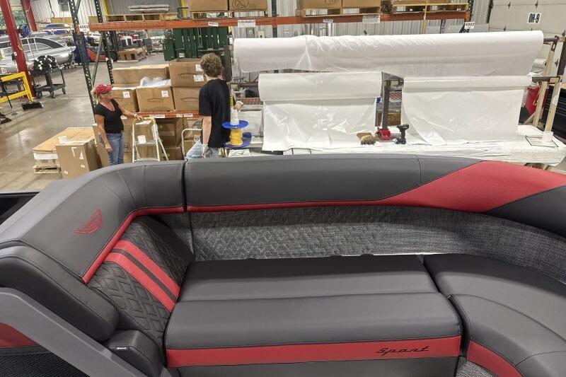 2026 Bennington 24 MFBSF boat interior with red and gray seating in a factory setting.