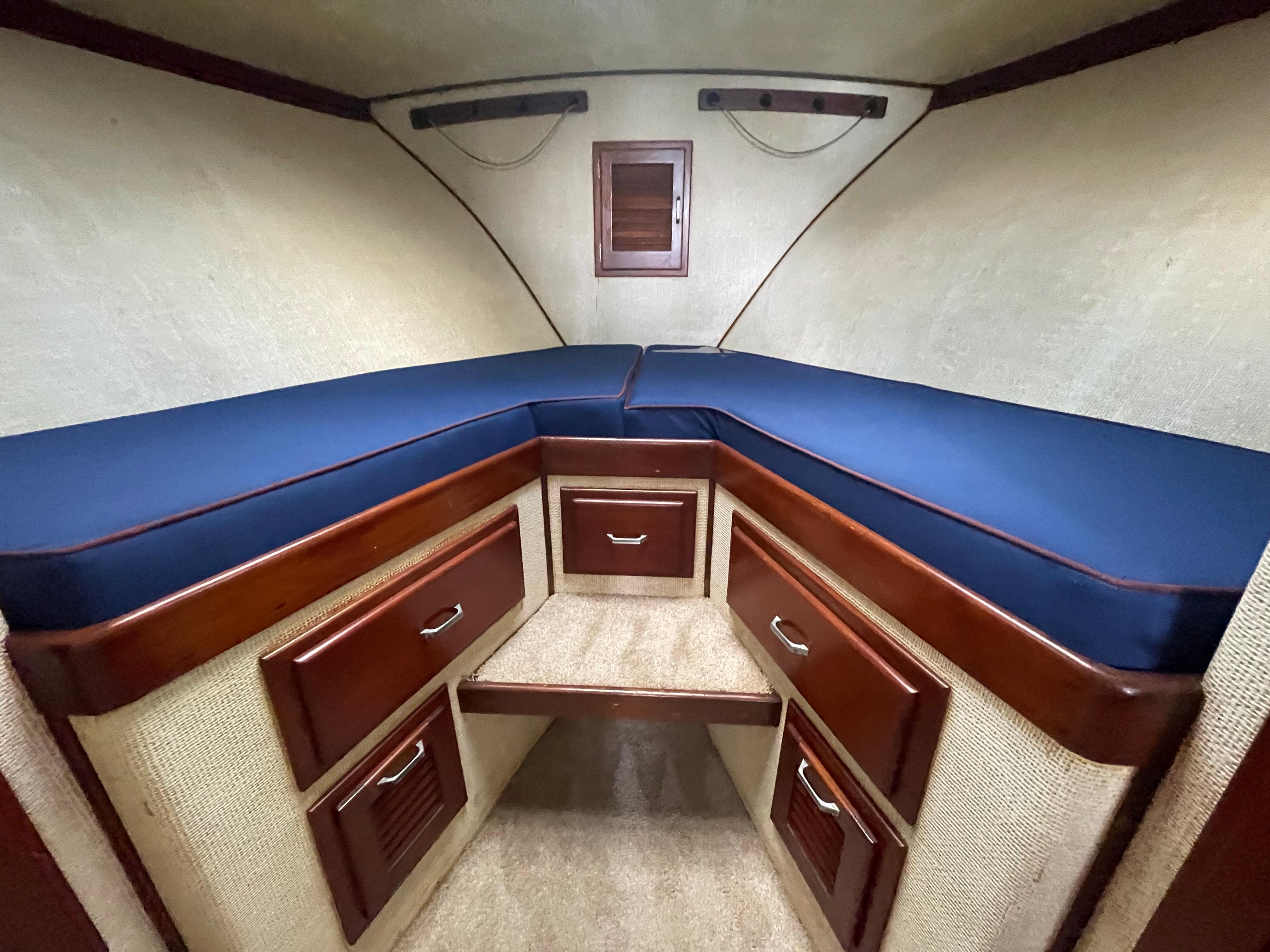 1975 Custom 36 Matlack Tournament SF cabin with blue cushions and wooden storage drawers.