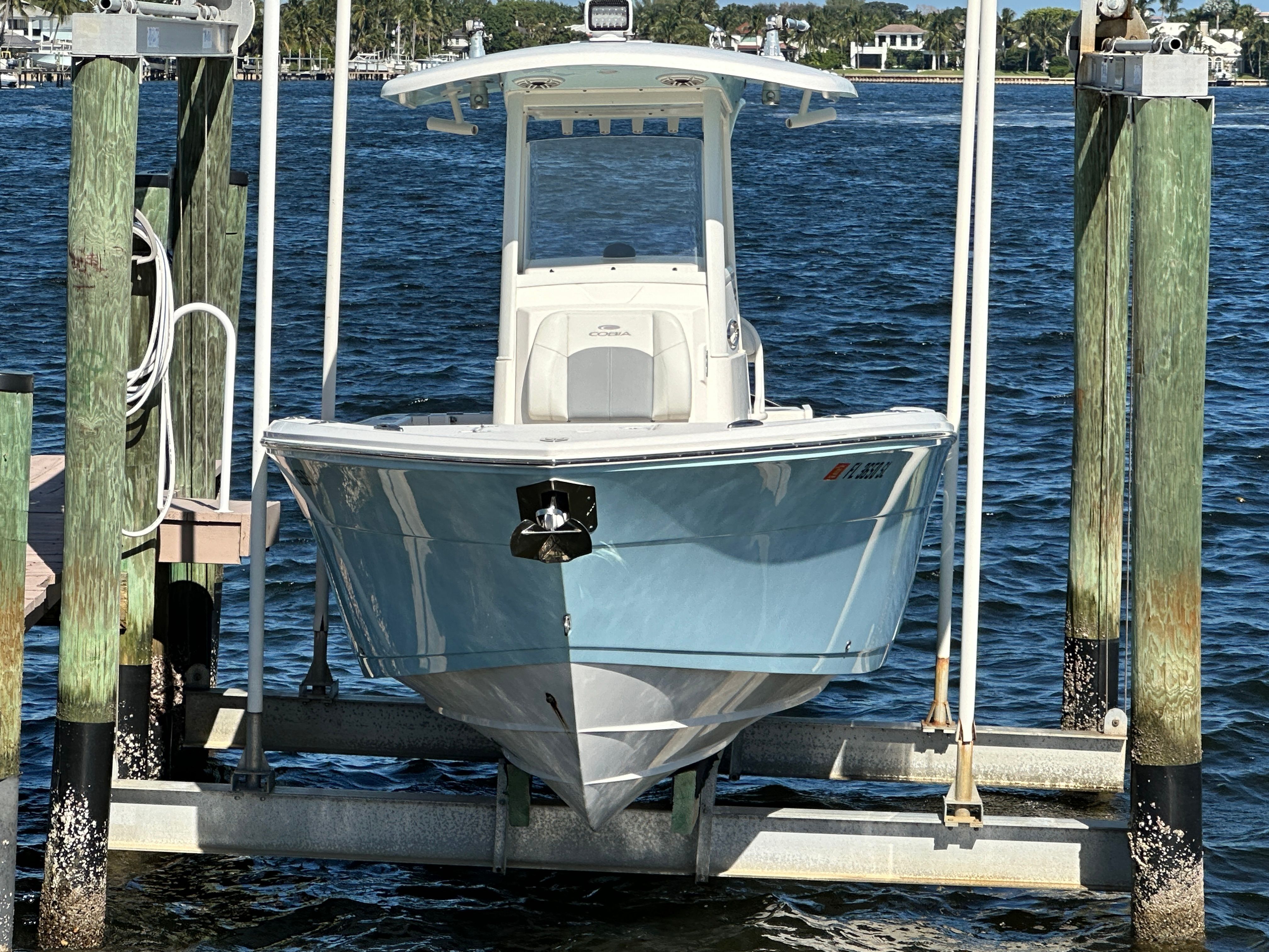 2022 Cobia 240 Center Console on a boat lift by the water.