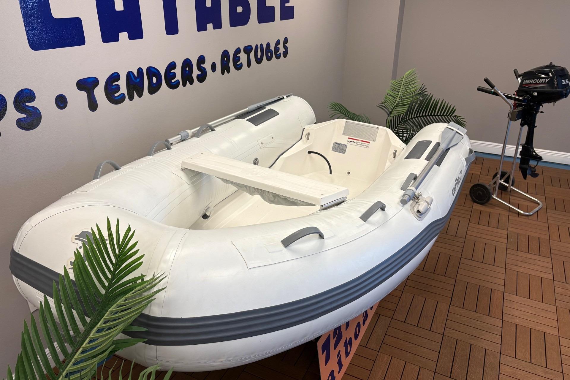 Inflatable Caribe L-9 boat, 2025 model, displayed indoors with outboard motor nearby.