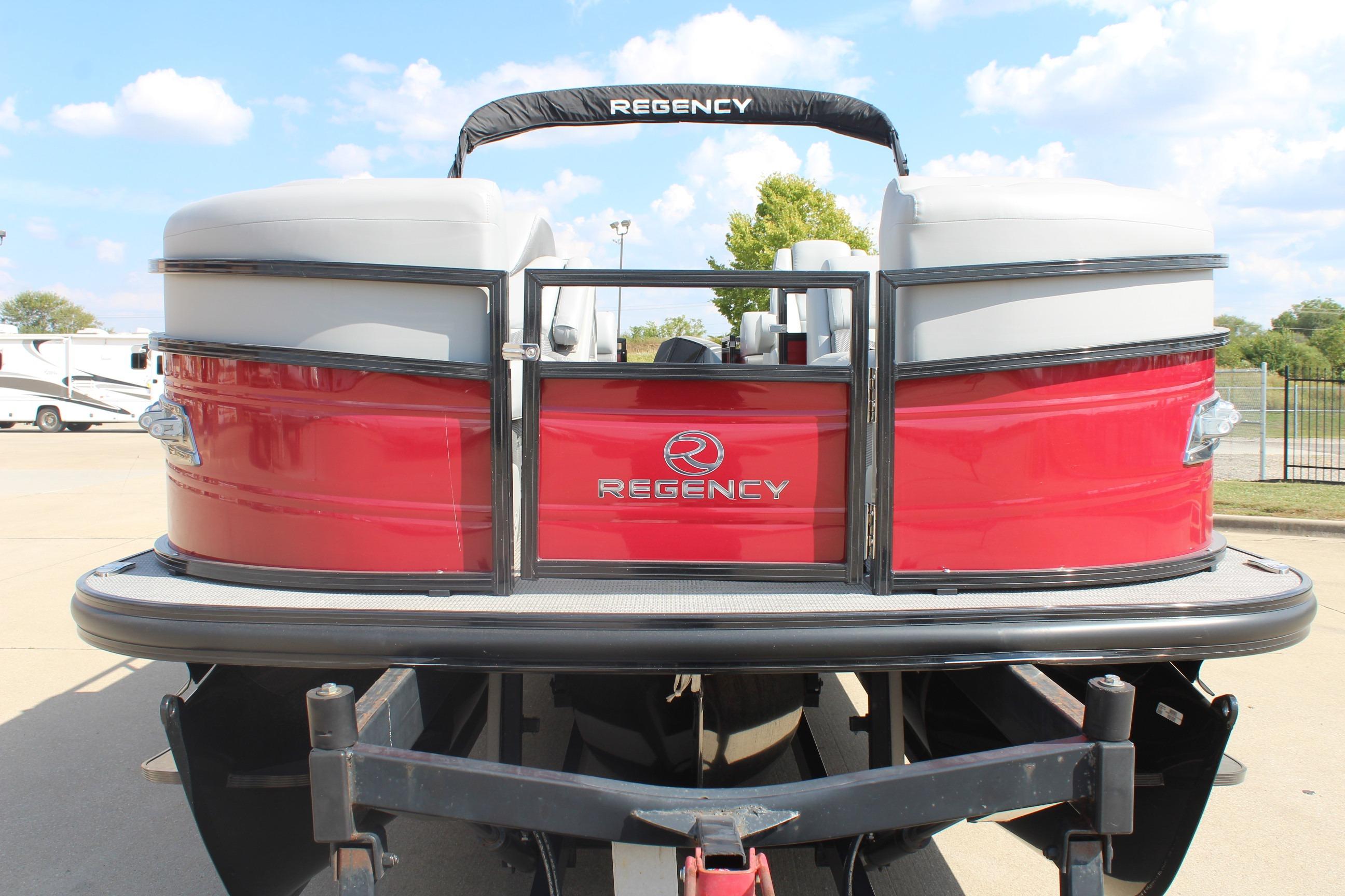 2025 Regency 230 DL3 pontoon boat, red exterior, parked outdoors under a blue sky.
