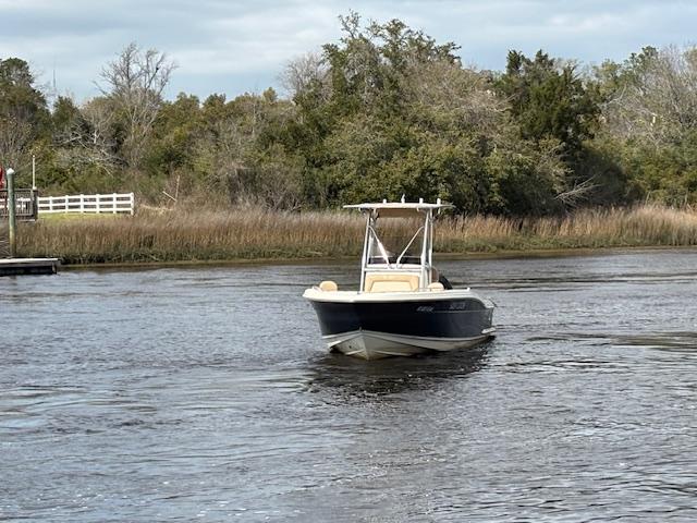 2022 Scout 215 XSF boat cruising on a calm river with lush greenery.