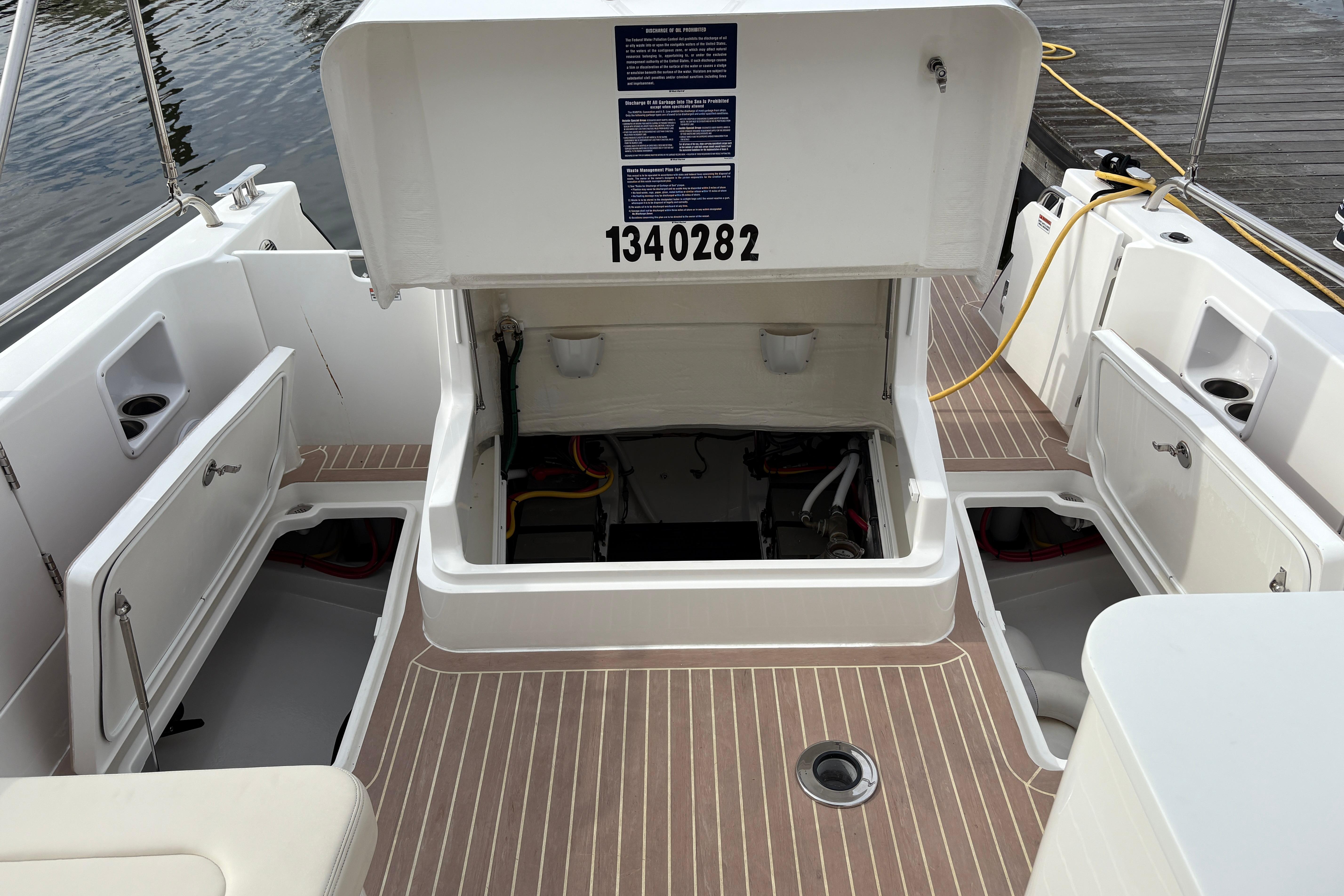 2023 MJM 35 boat with open engine compartment and storage, docked by the water.