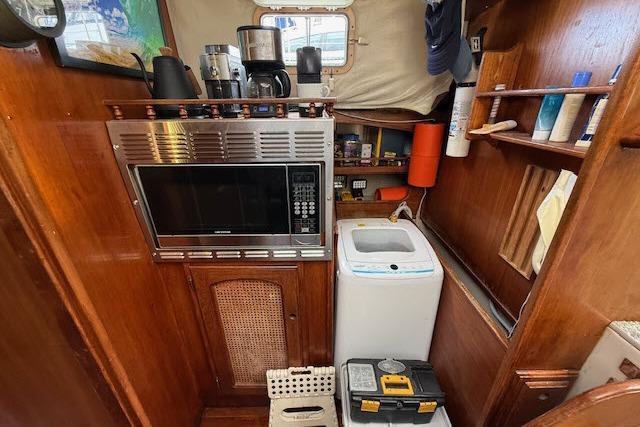 Interior of 1982 Lancer 45 Motorsailer with microwave, washing machine, and wooden cabinetry.