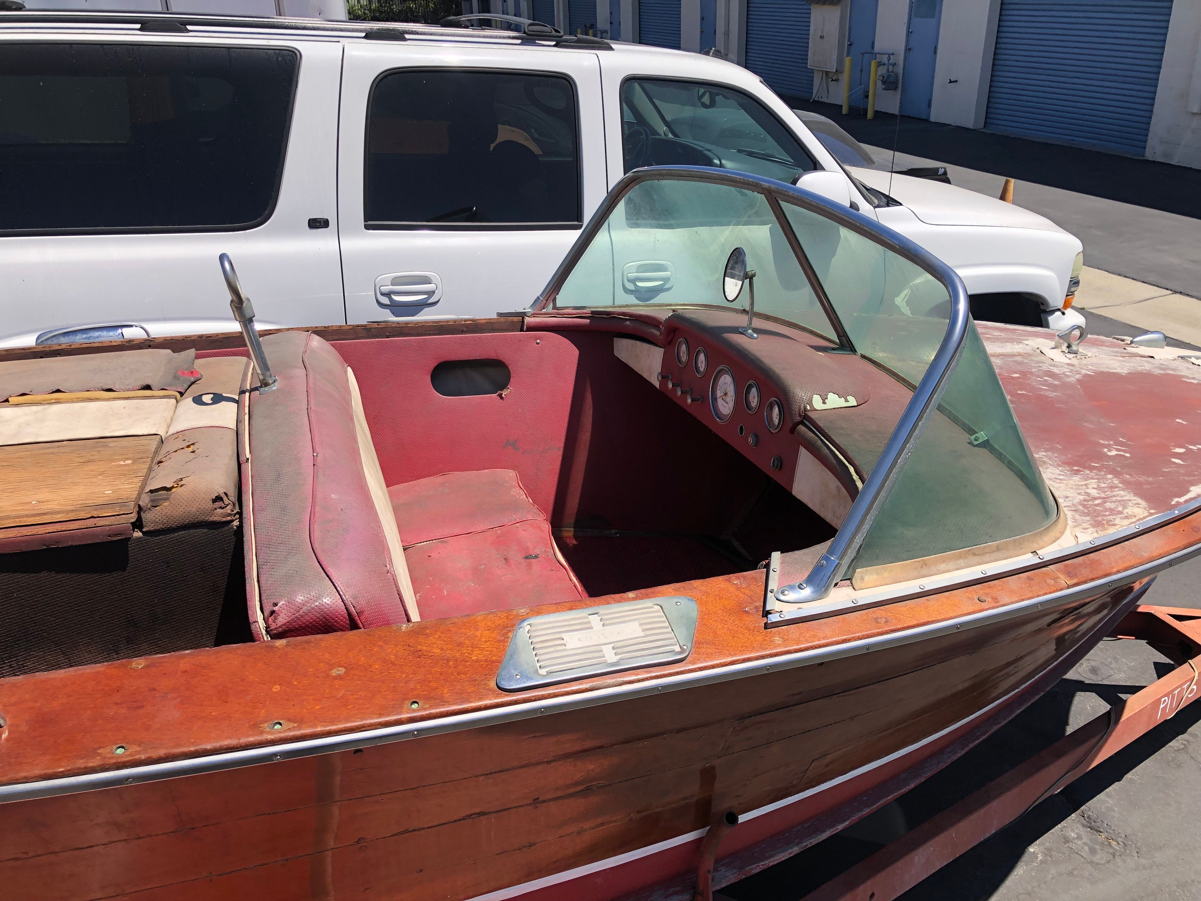 A 1960 Century Resorter with red interior and wooden exterior, parked next to a white vehicle.