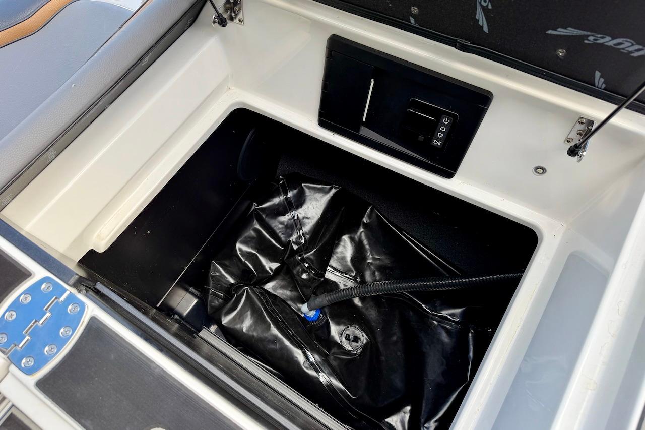 Storage compartment of 2025 Tigé Ultré 25ZX boat with black interior and control panel.