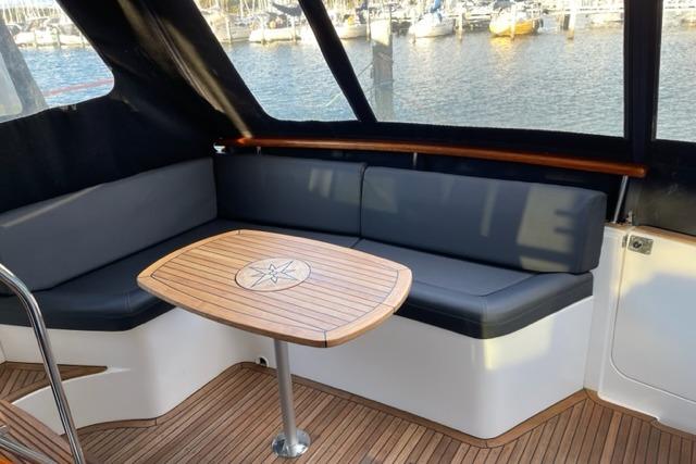1998 Storebro 430 Royal Cruiser interior with seating and wooden table by the water.