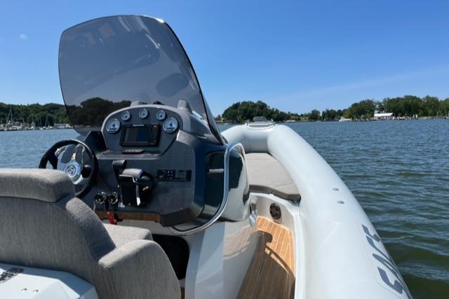 2024 SACS Strider 900 boat on a lake with a clear blue sky.