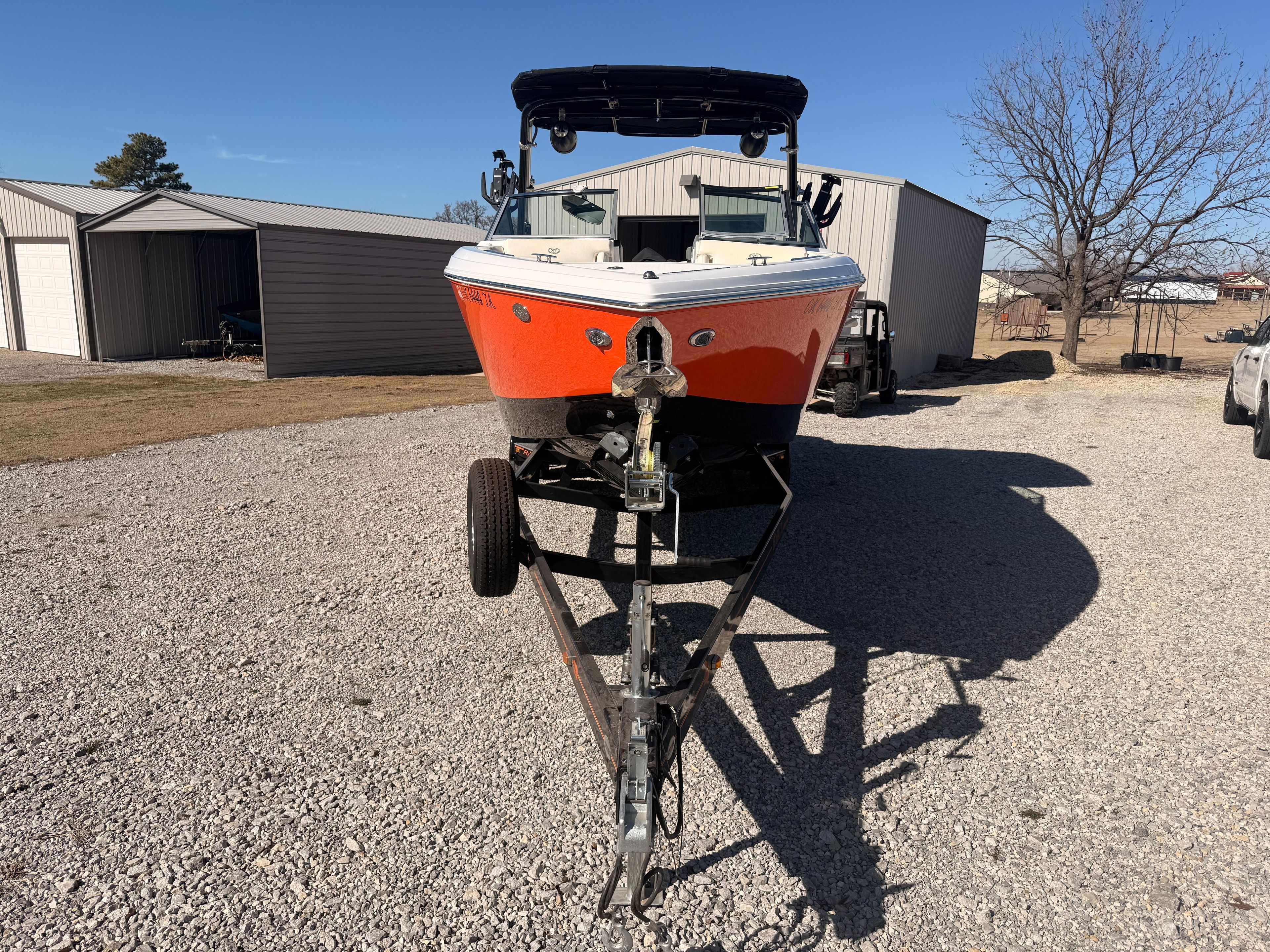 An orange 2019 Cobalt R7 Surf boat on a trailer in a gravel lot.