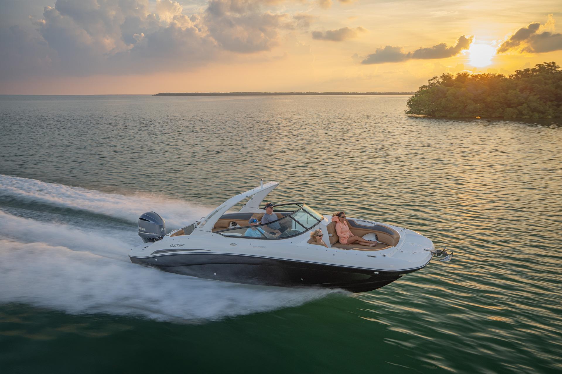 2026 Hurricane SunDeck 2690 OB cruising at sunset on serene waters.