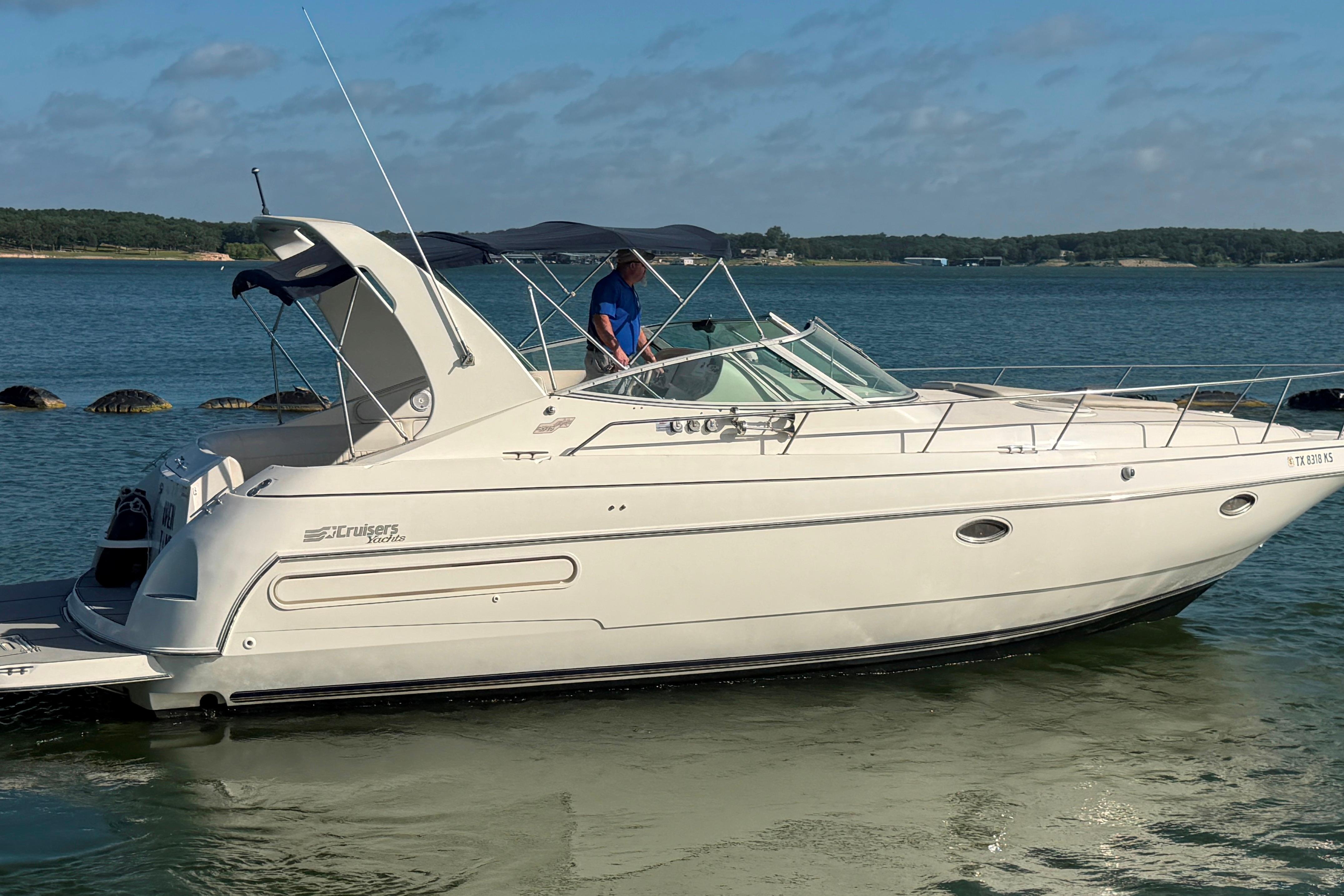 1997 Cruisers 3575 yacht docked on a serene lake under a clear sky.