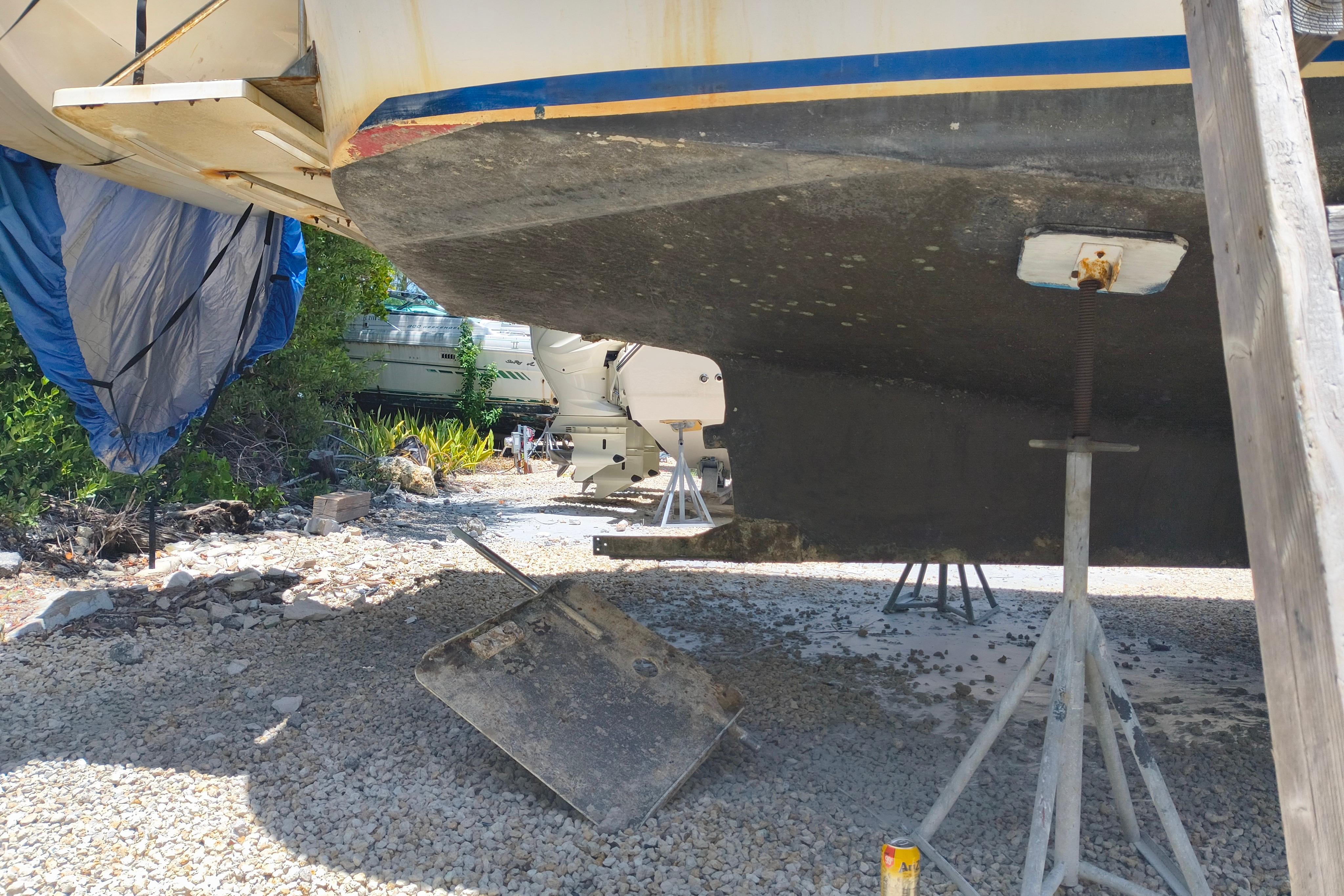1984 Kadey-Krogen Manatee boat hull on stands, undergoing maintenance on gravel surface.