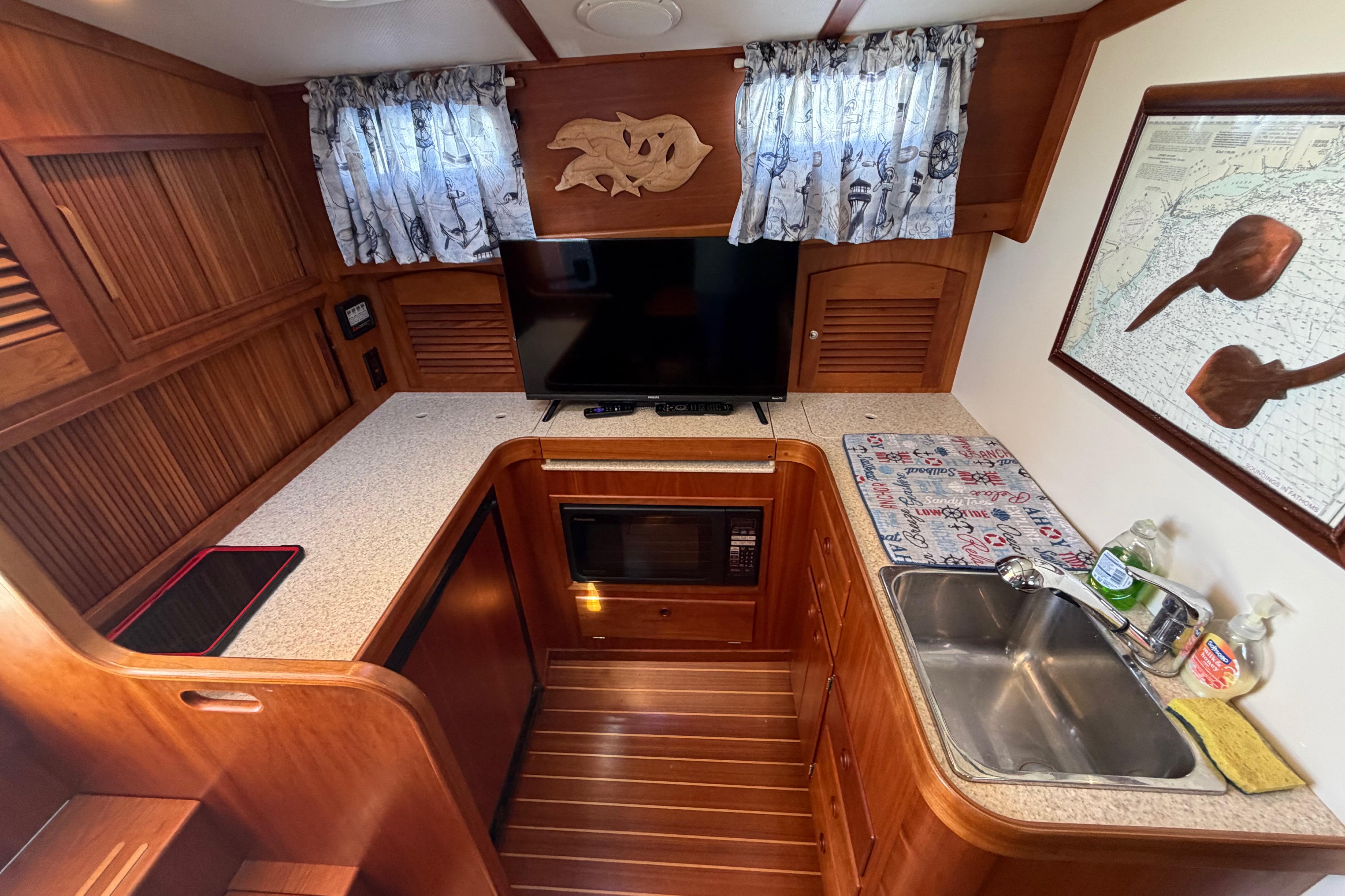 Interior of 2000 Sabreline 36 Express yacht with kitchenette, TV, and wooden cabinetry.