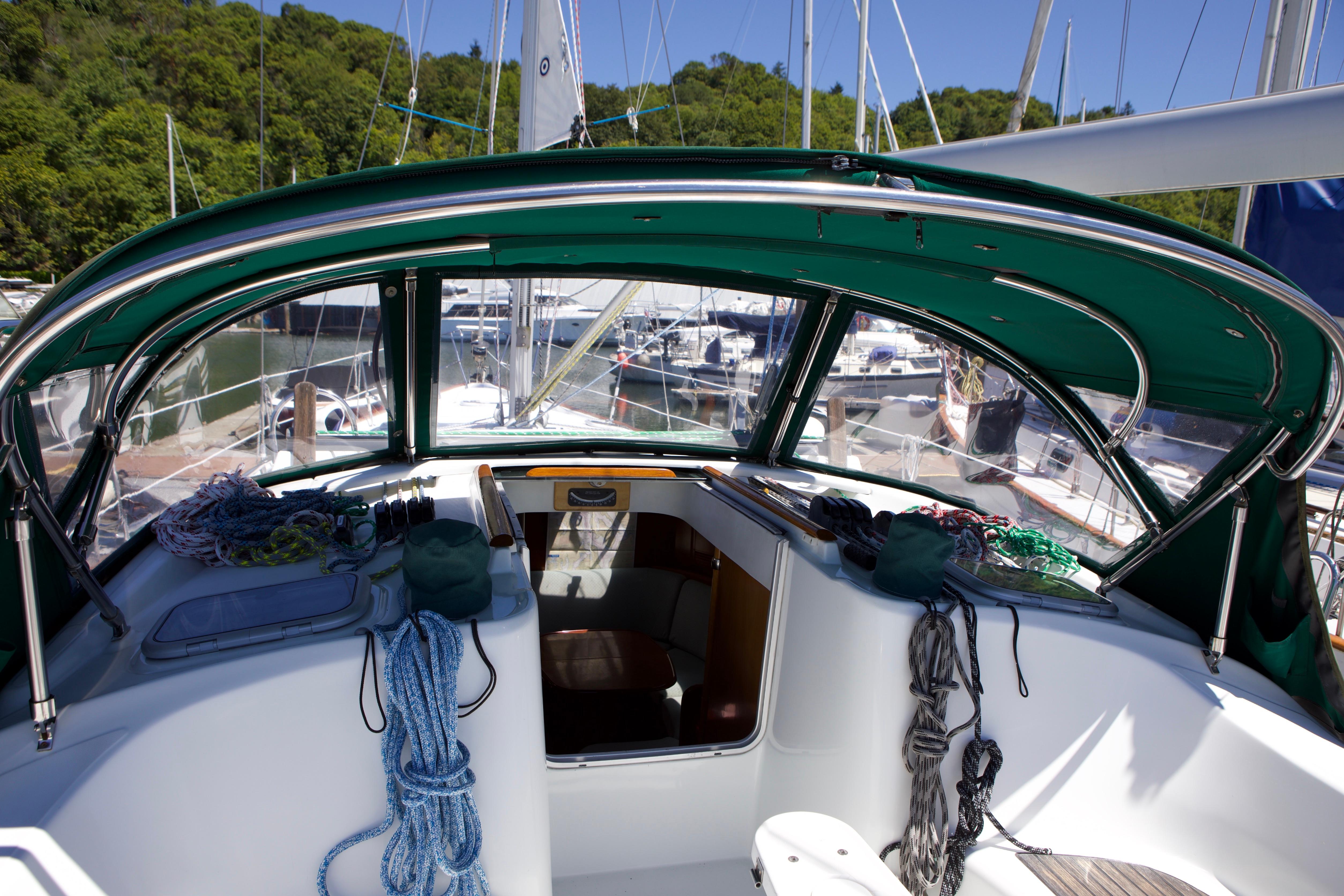 Cockpit view of 2005 Beneteau 423 sailboat with green canopy and marina background.