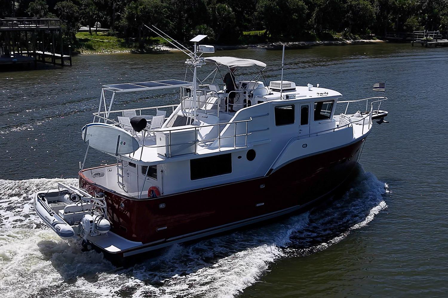 2003 Magna Marine Nova Scotia 47 yacht cruising on a river, showcasing sleek design and spacious deck.