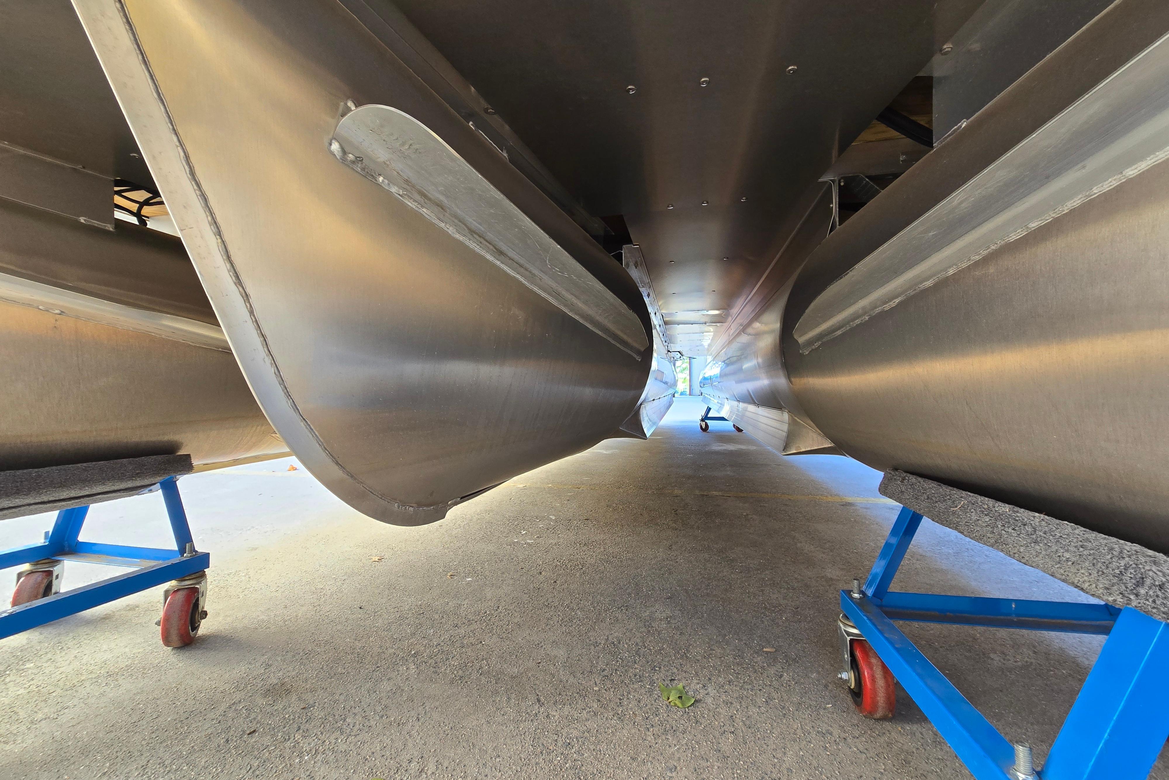 Underneath view of 2024 Godfrey Sweetwater 2486 SB pontoon boat on blue stands.