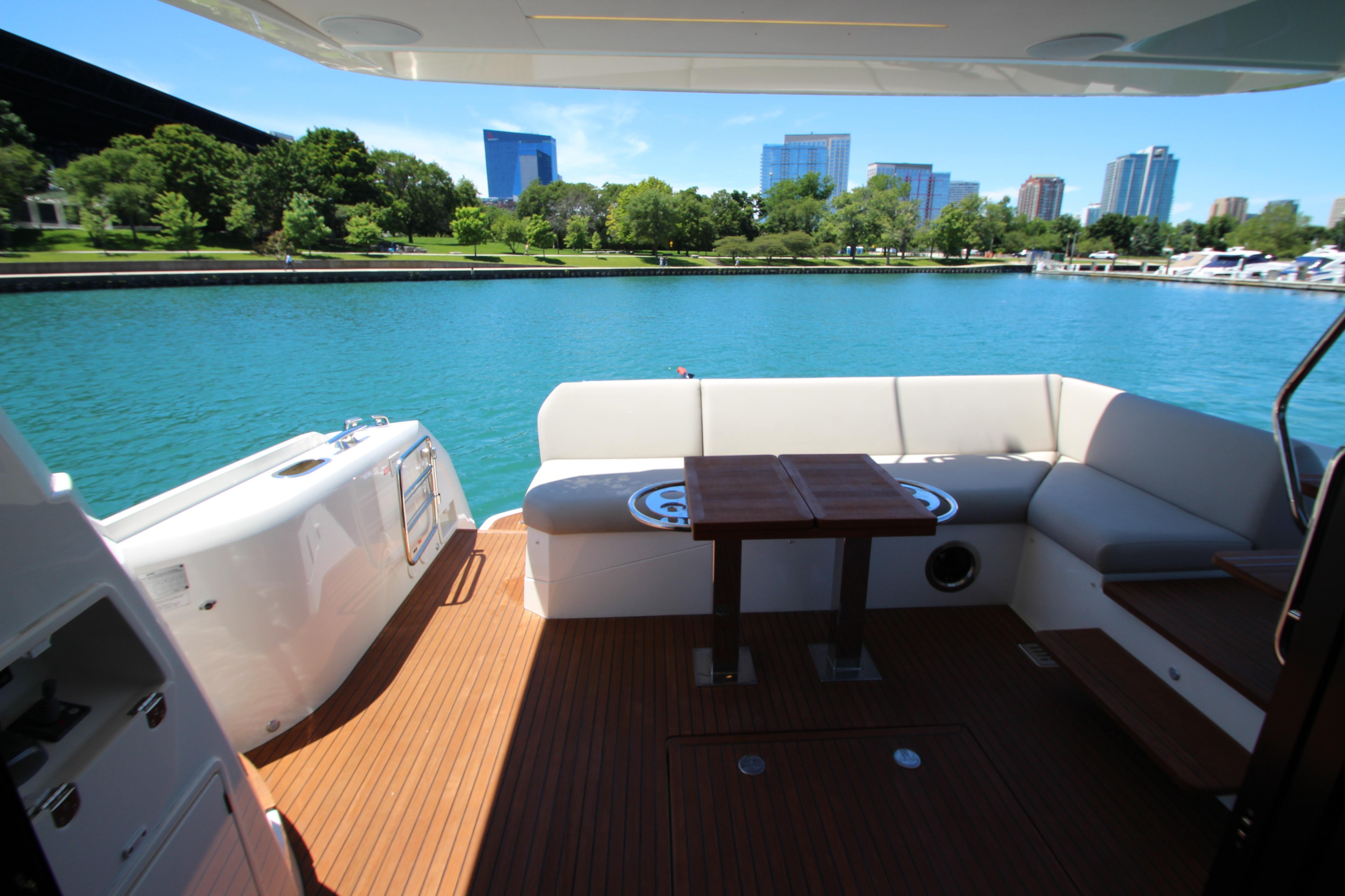 Luxurious 2022 Prestige 520 yacht deck with seating, overlooking serene waterfront and cityscape.