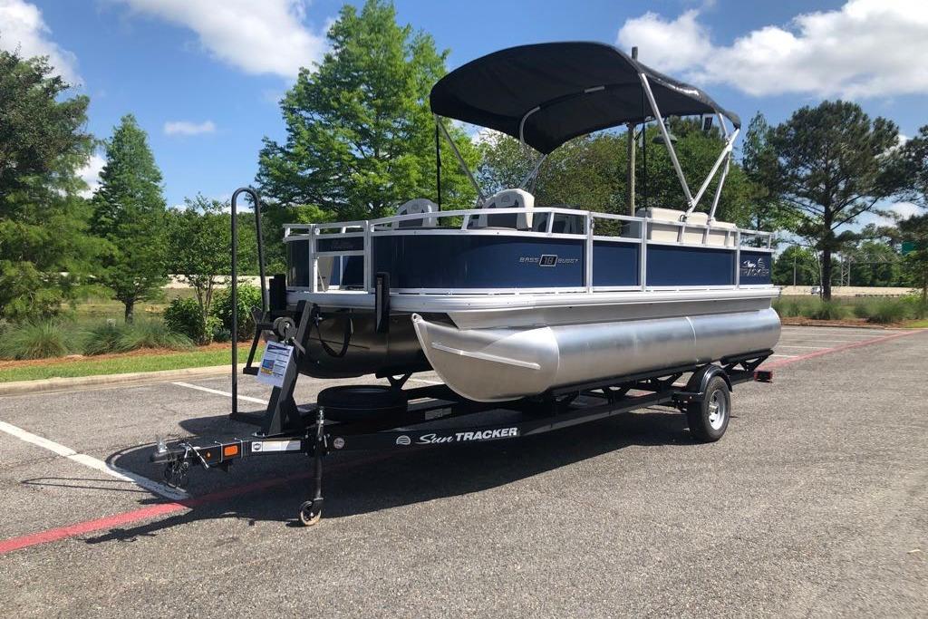 2026 Sun Tracker Bass Buggy 18 DLX pontoon boat on trailer in parking lot.