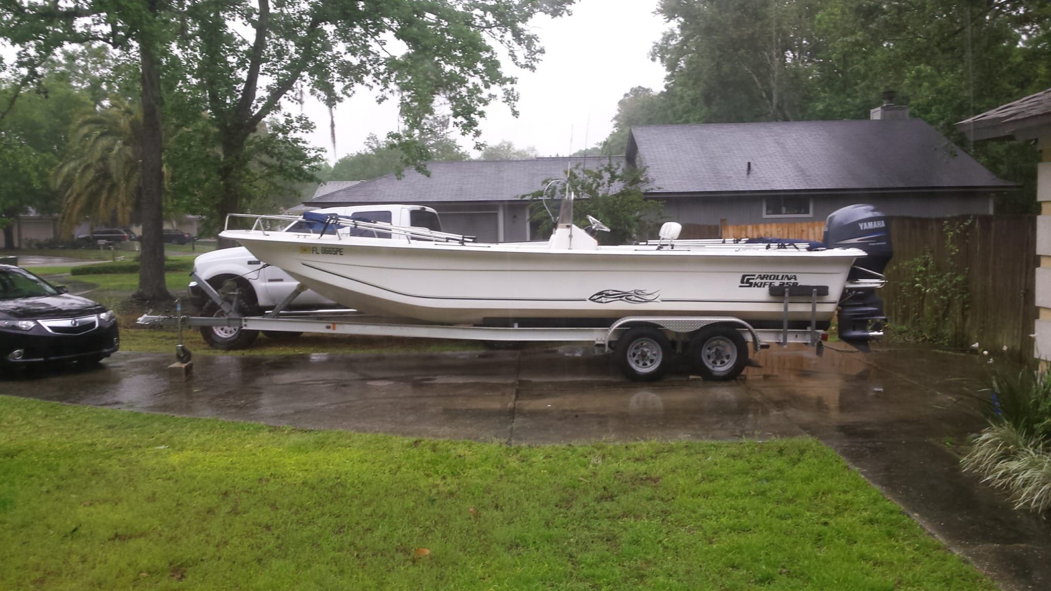 A 2011 Carolina Skiff 258 DLV boat on a trailer in a driveway.