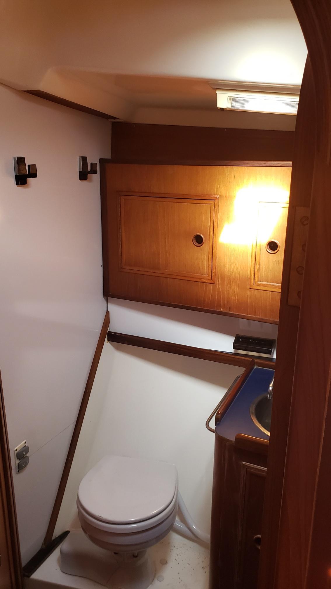 1983 Wauquiez 38 MKI yacht bathroom with wooden cabinets and compact toilet.