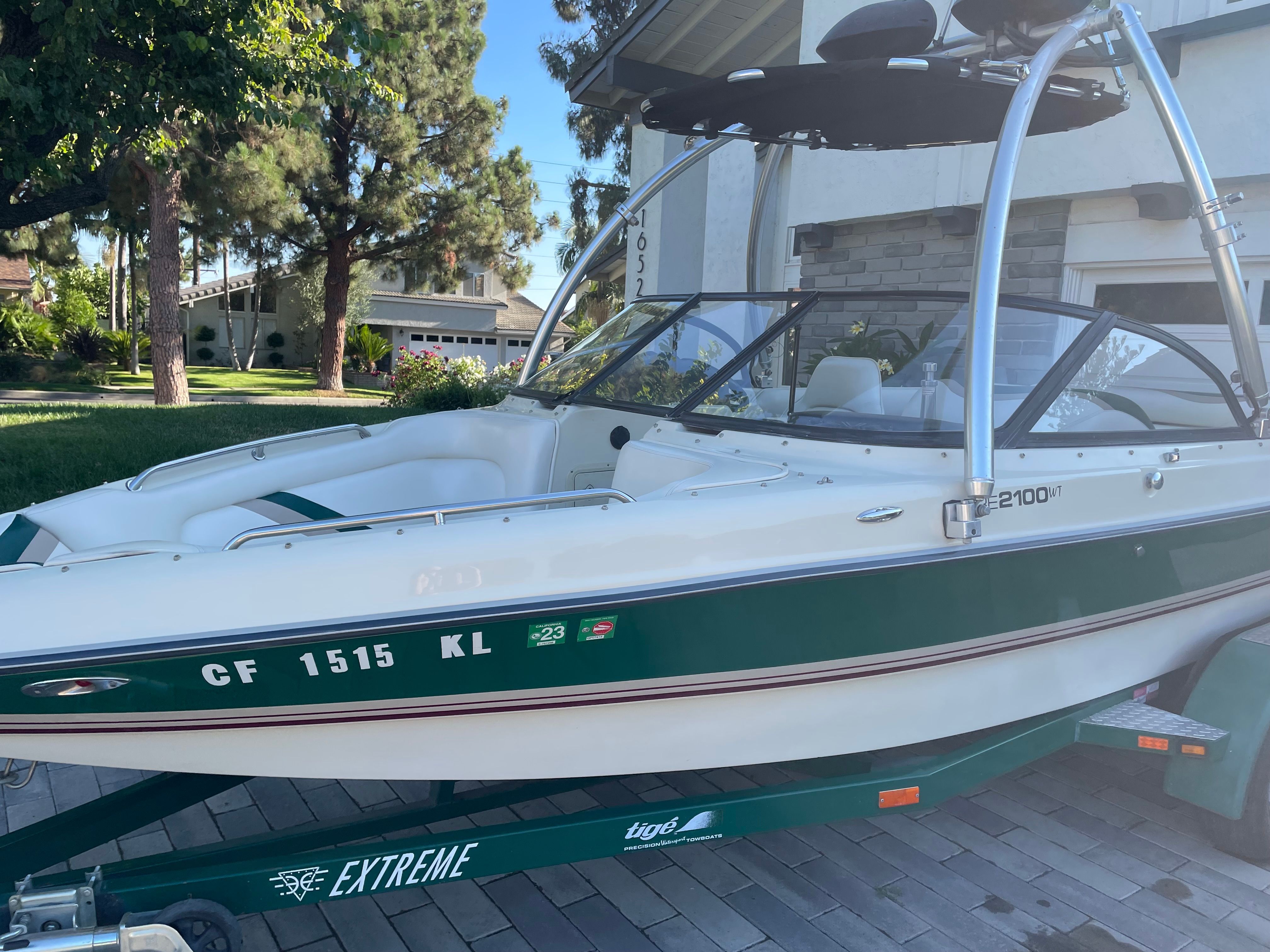 A 1998 Tigé Pre 2100 boat on a trailer in a residential area.