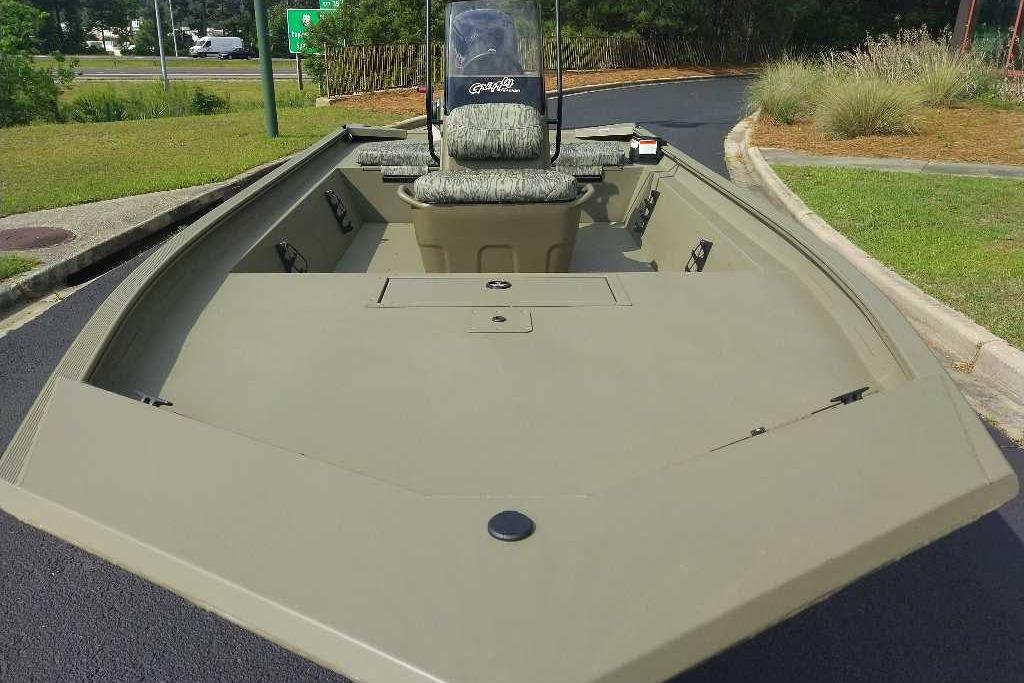 2026 Tracker Grizzly 1860 CC boat with camouflage seating, parked on pavement.