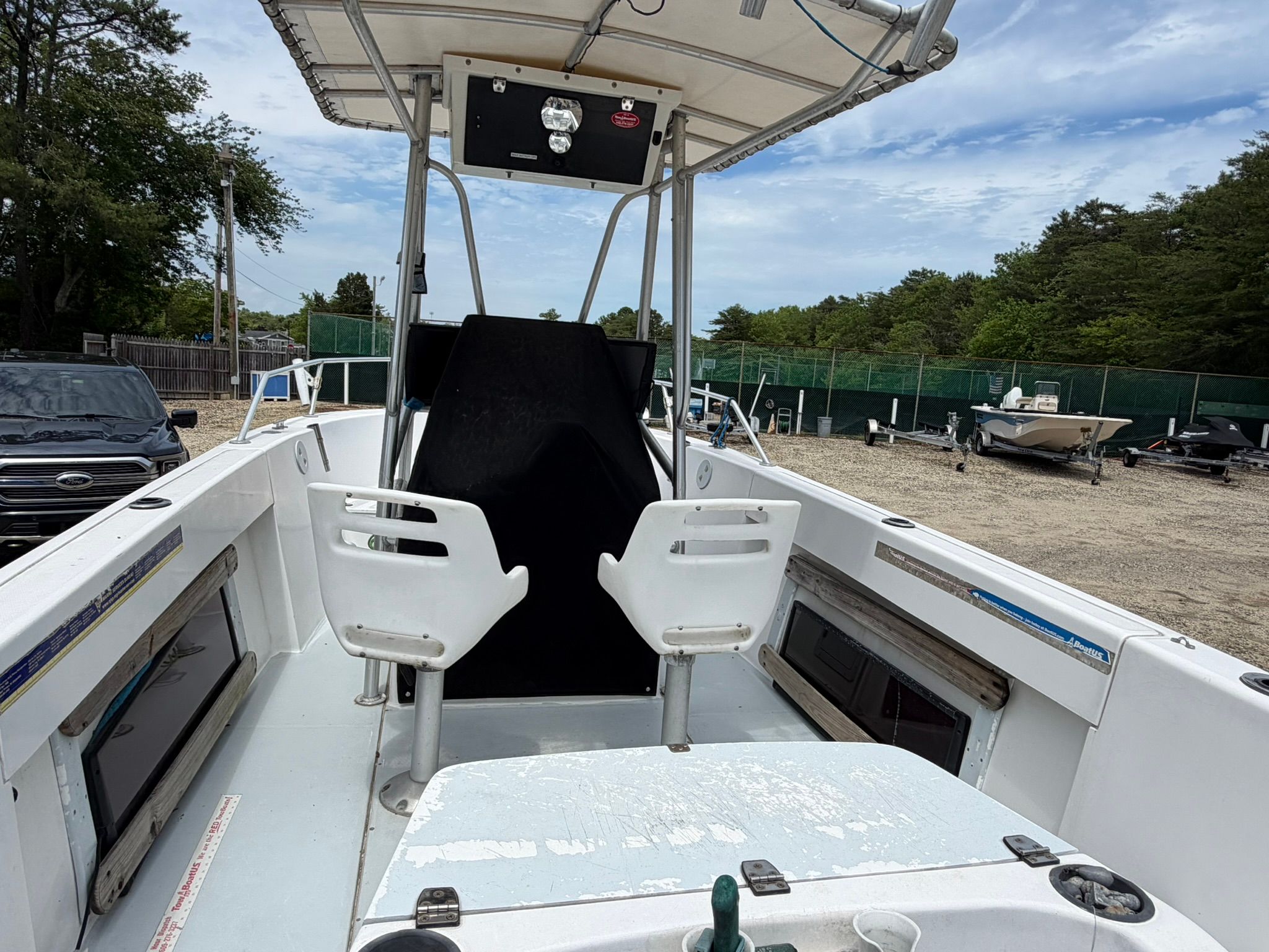 An Angler boat on dry dock with two white seats and a helm station.