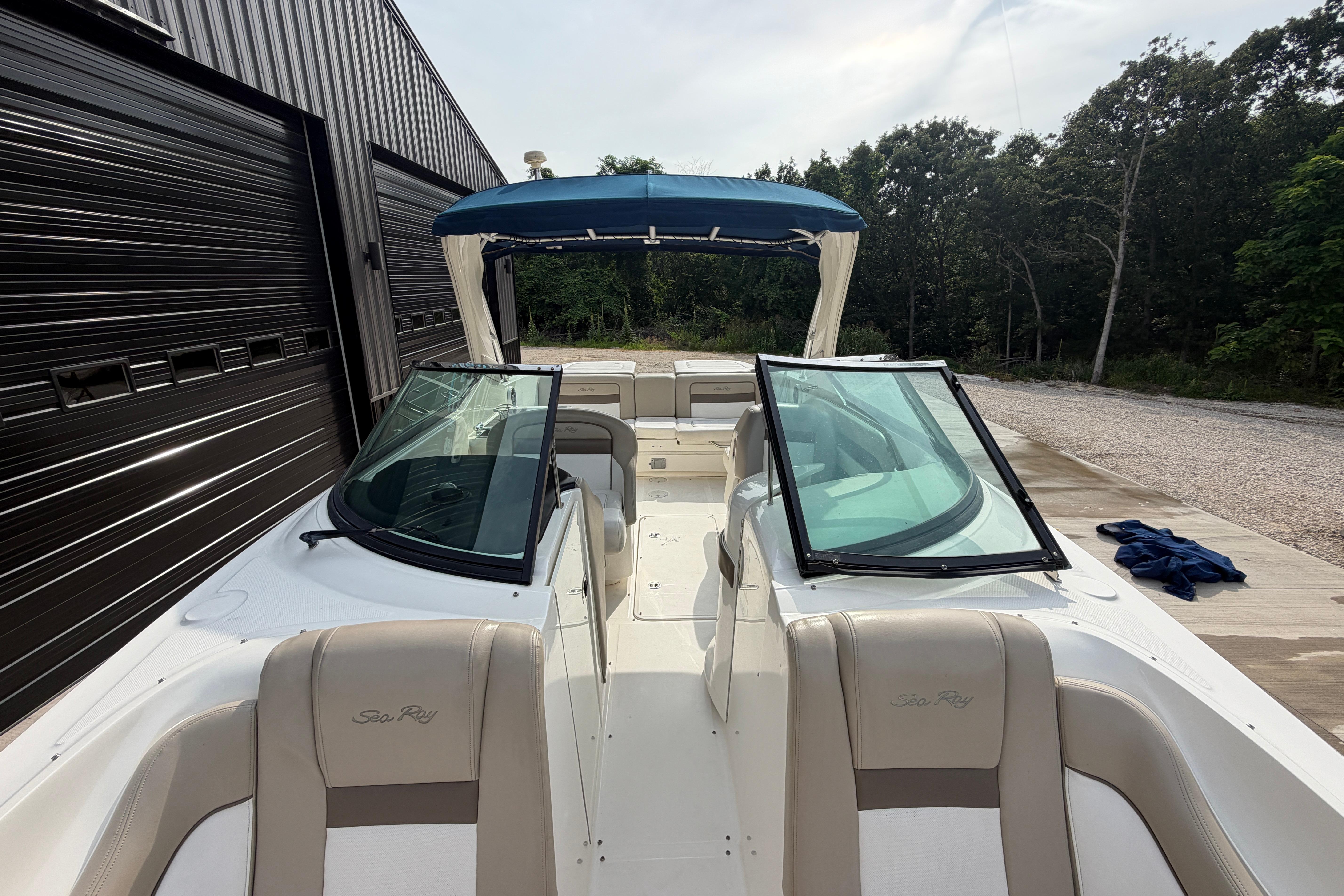 2013 Sea Ray 300 SLX boat with open cockpit and blue canopy, parked outdoors.