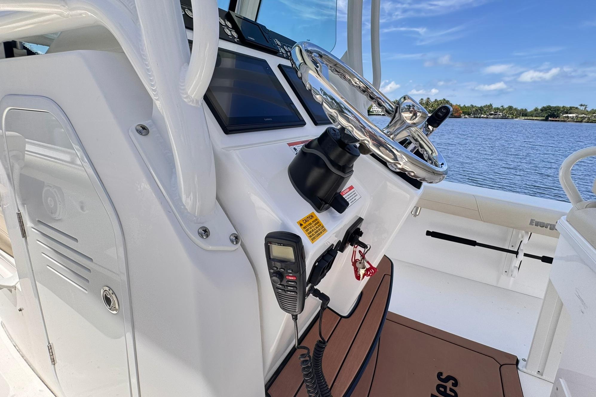 Center console of 2018 Everglades 253 boat with steering wheel and controls, overlooking water.