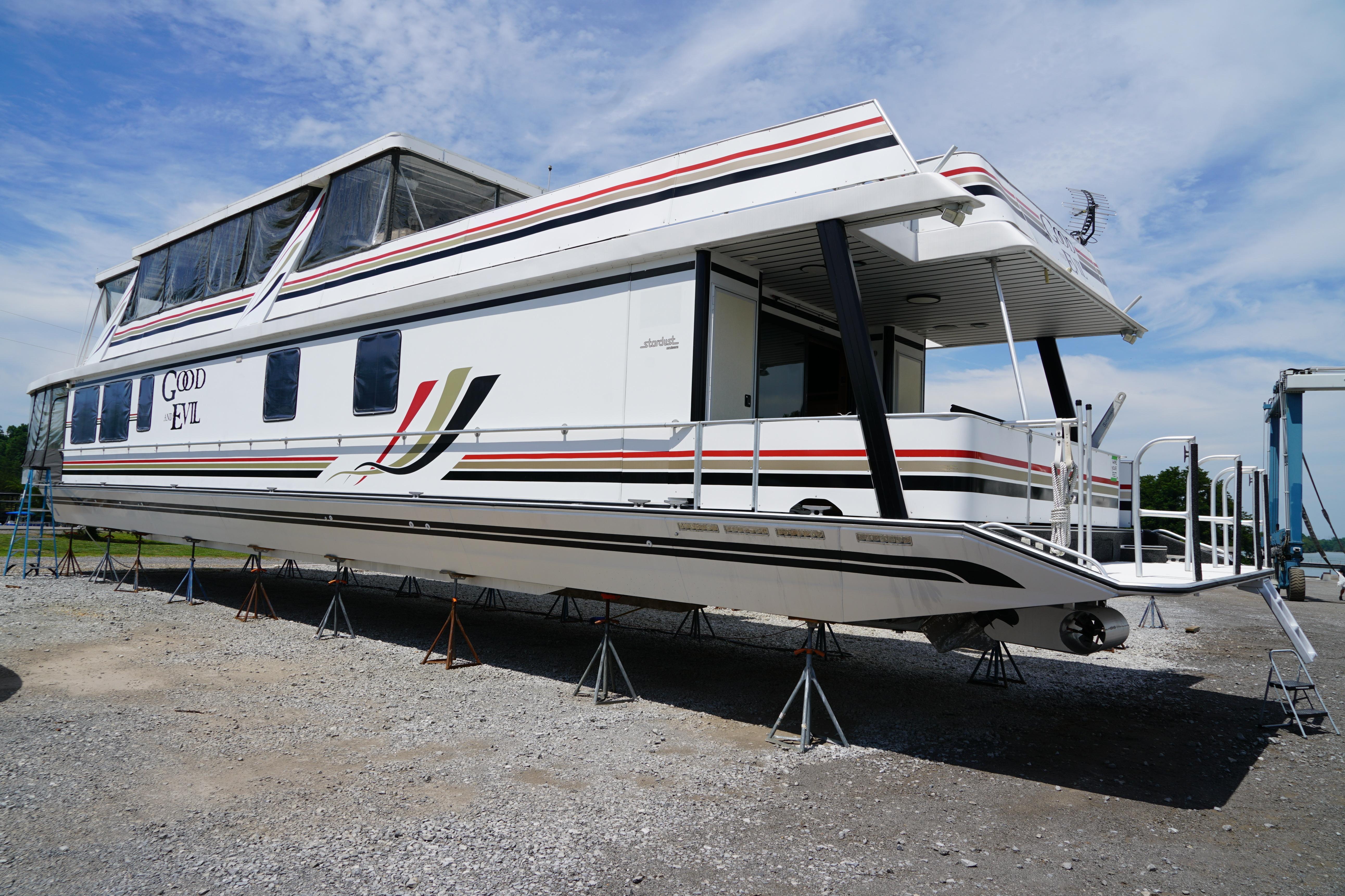 2000 Stardust Cruisers 83'x17' houseboat on stands, featuring sleek design and vibrant stripes.