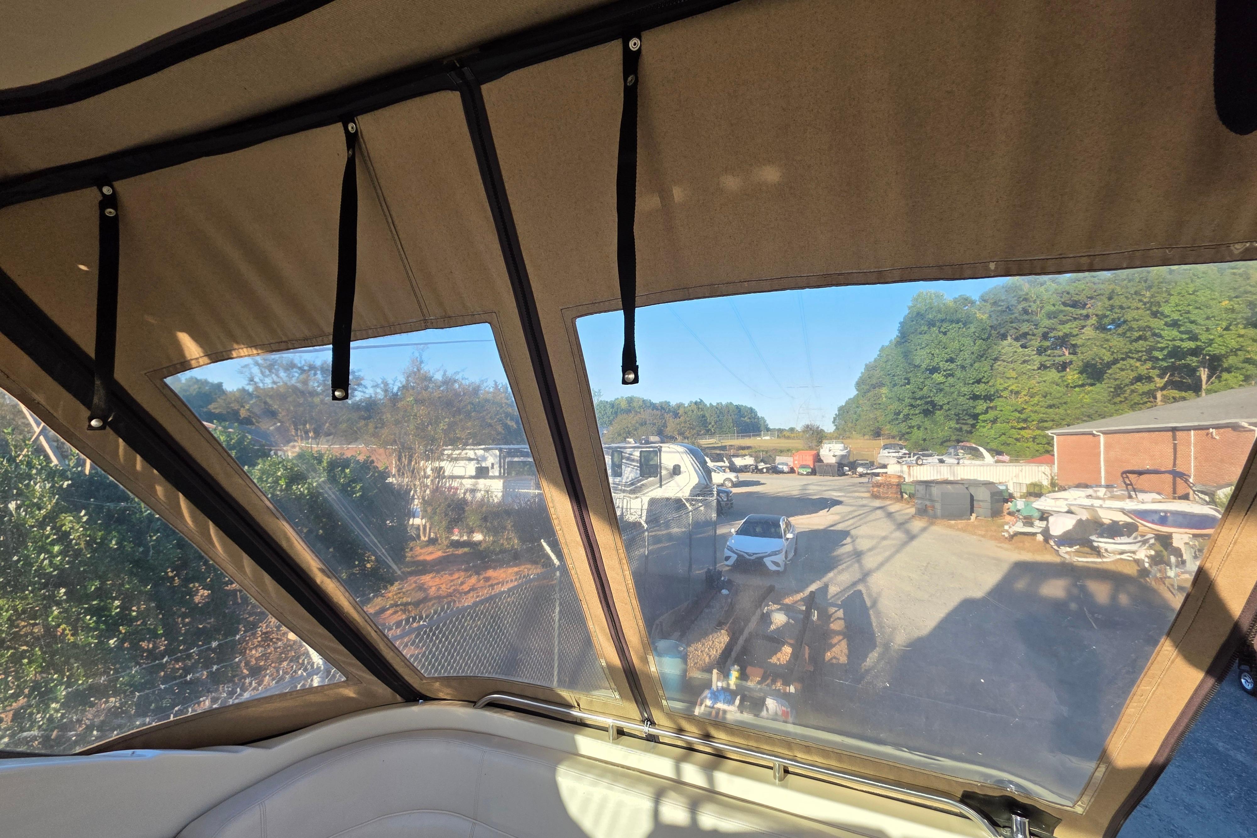 Interior view from a 1998 Maxum 3700 SCR boat, overlooking a marina with vehicles.