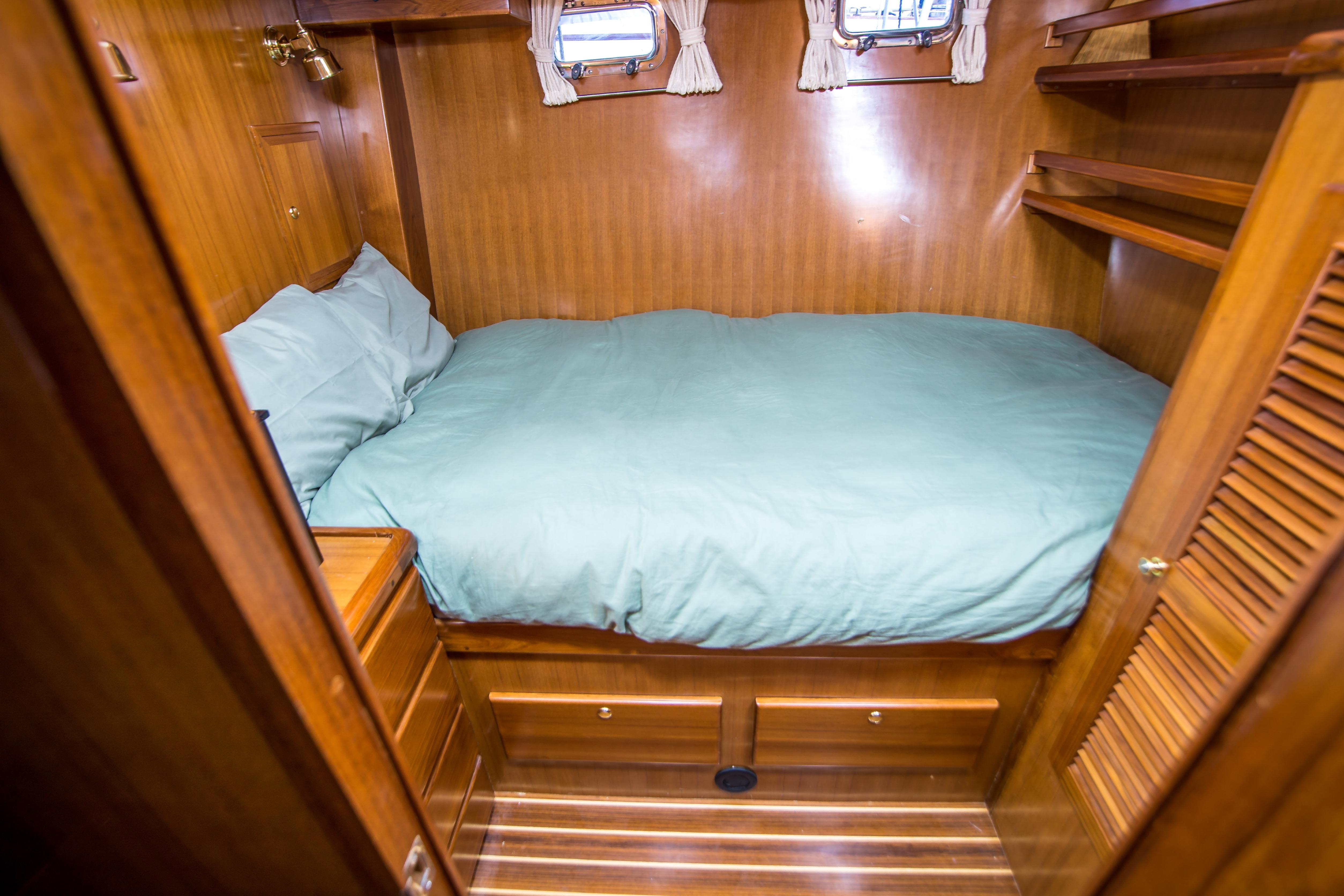 Cozy cabin interior of 2008 North Pacific 43 Pilothouse with wooden finish and bed.