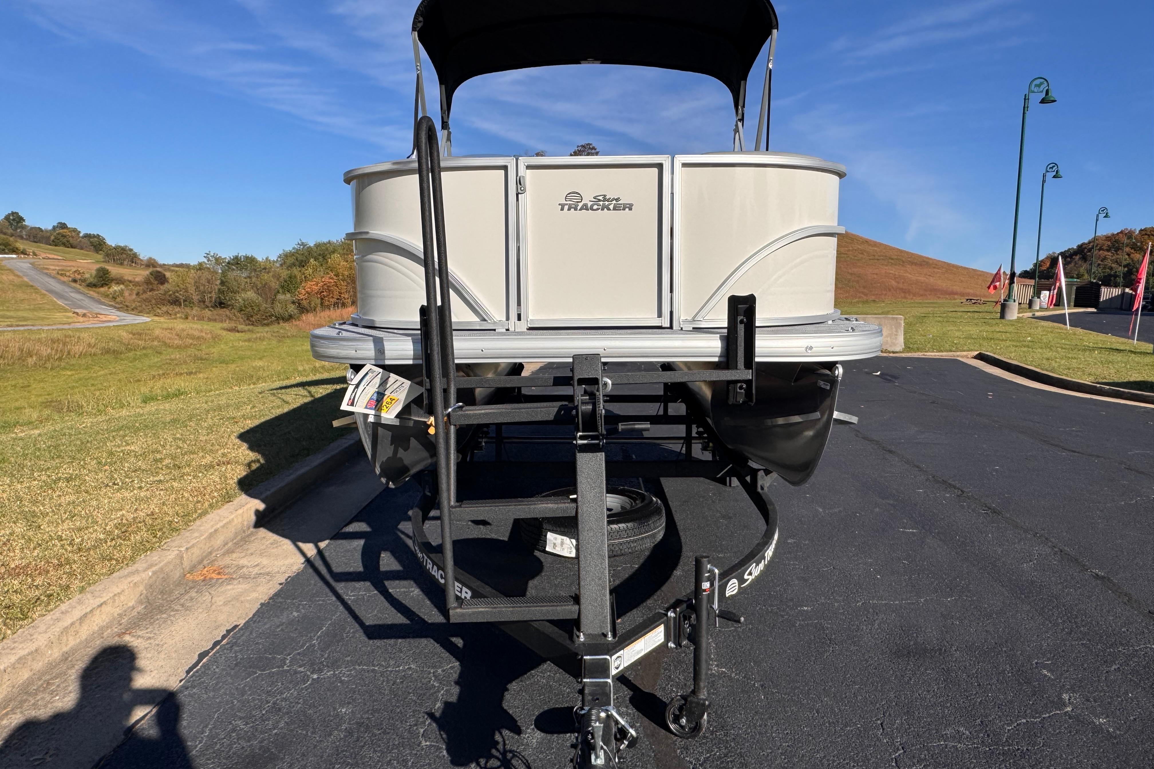 2026 Sun Tracker Party Barge 16 DLX pontoon boat on trailer, parked outdoors.