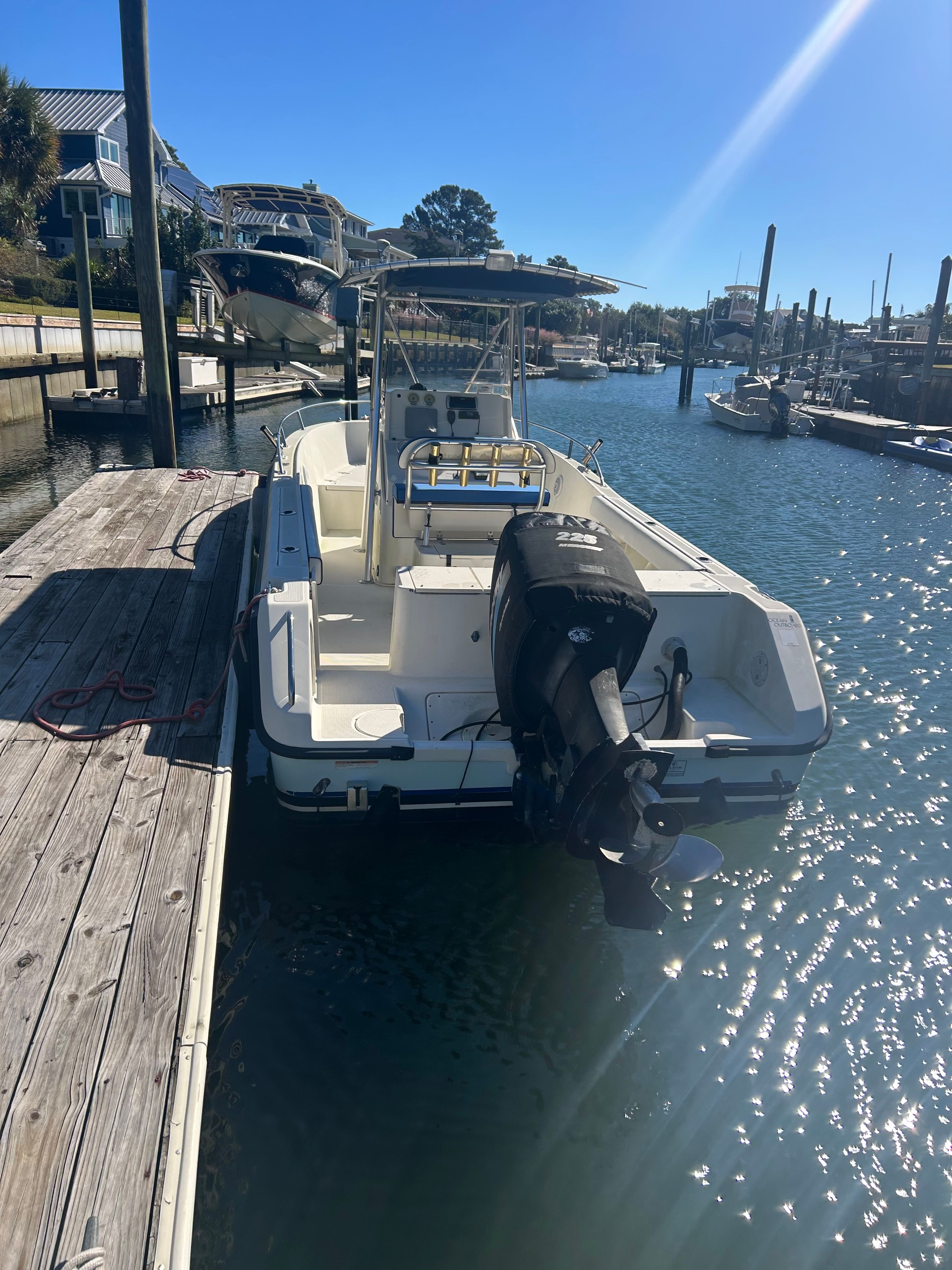 2002 Pursuit 2470 Center Console at dock, featuring outboard motor and sunshade.