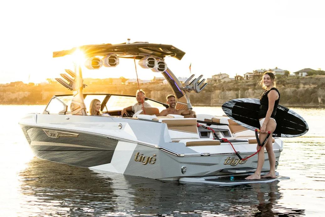 Manufacturer Provided Image: 2024 Tigé Ultré 25ZX boat with people enjoying water activities at sunset.