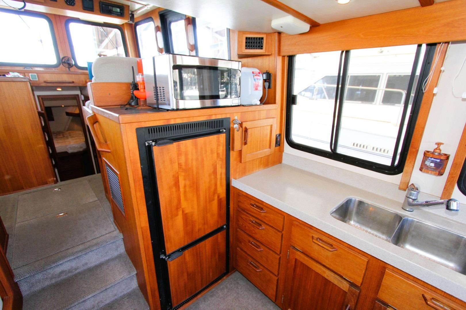 Interior of 2002 Nordic Tug 37 featuring a compact kitchen with wooden cabinetry and appliances.