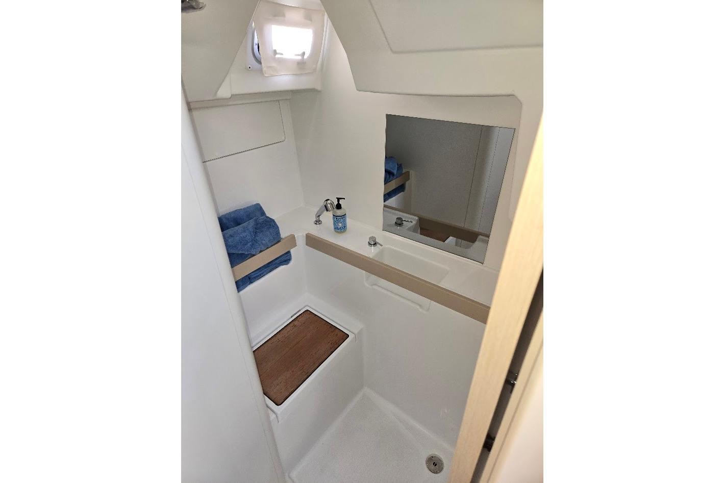 2023 Beneteau Oceanis 38.1 bathroom with mirror, sink, and wooden accents.