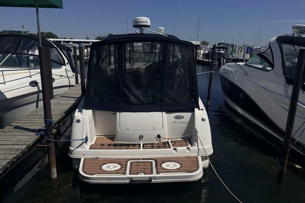 2001 Monterey 282 Cruiser docked at marina, rear view with canopy and wooden deck.