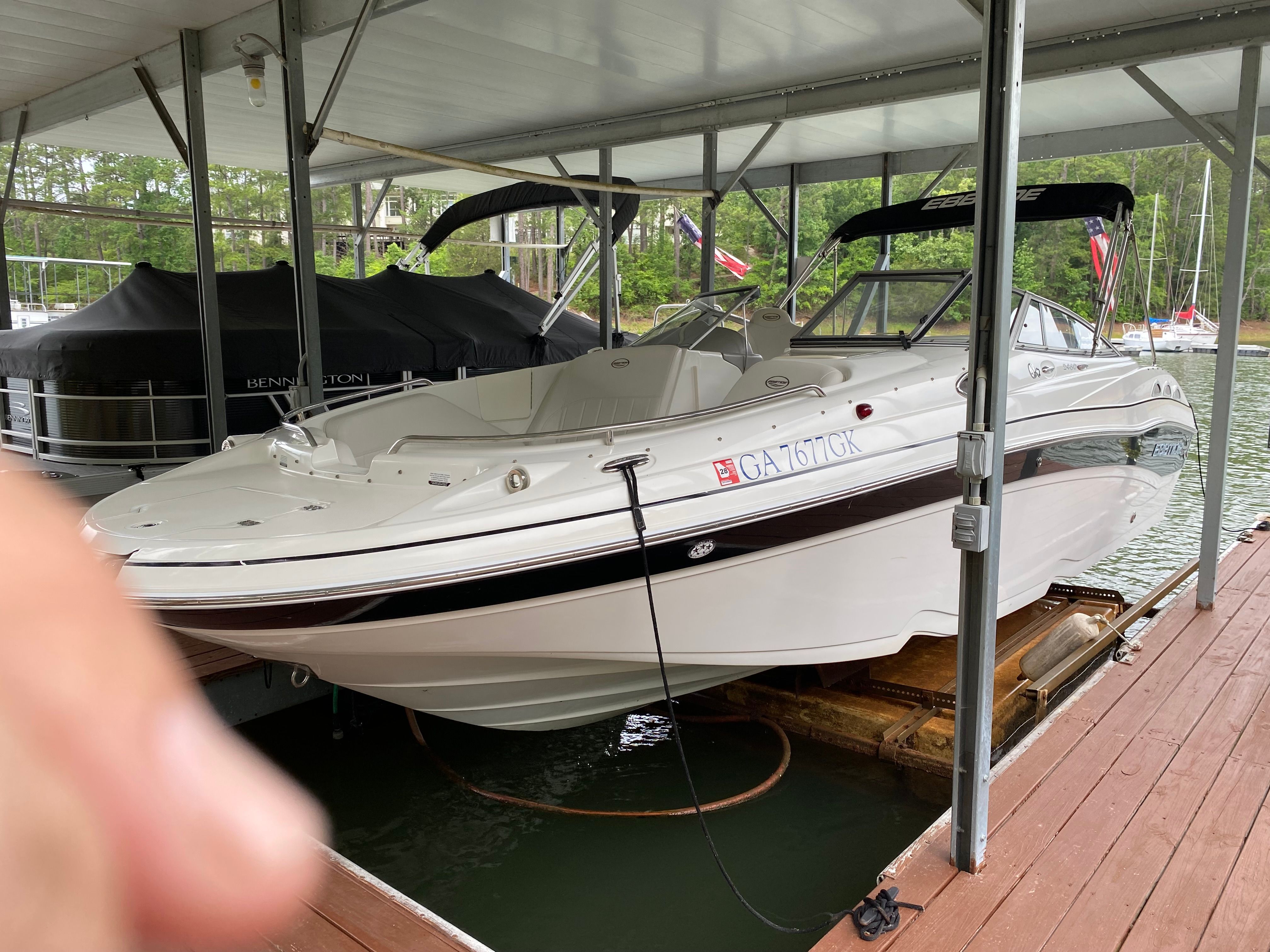 A white 2007 Ebbtide 2460 Z-Trak boat is docked under a covered area.