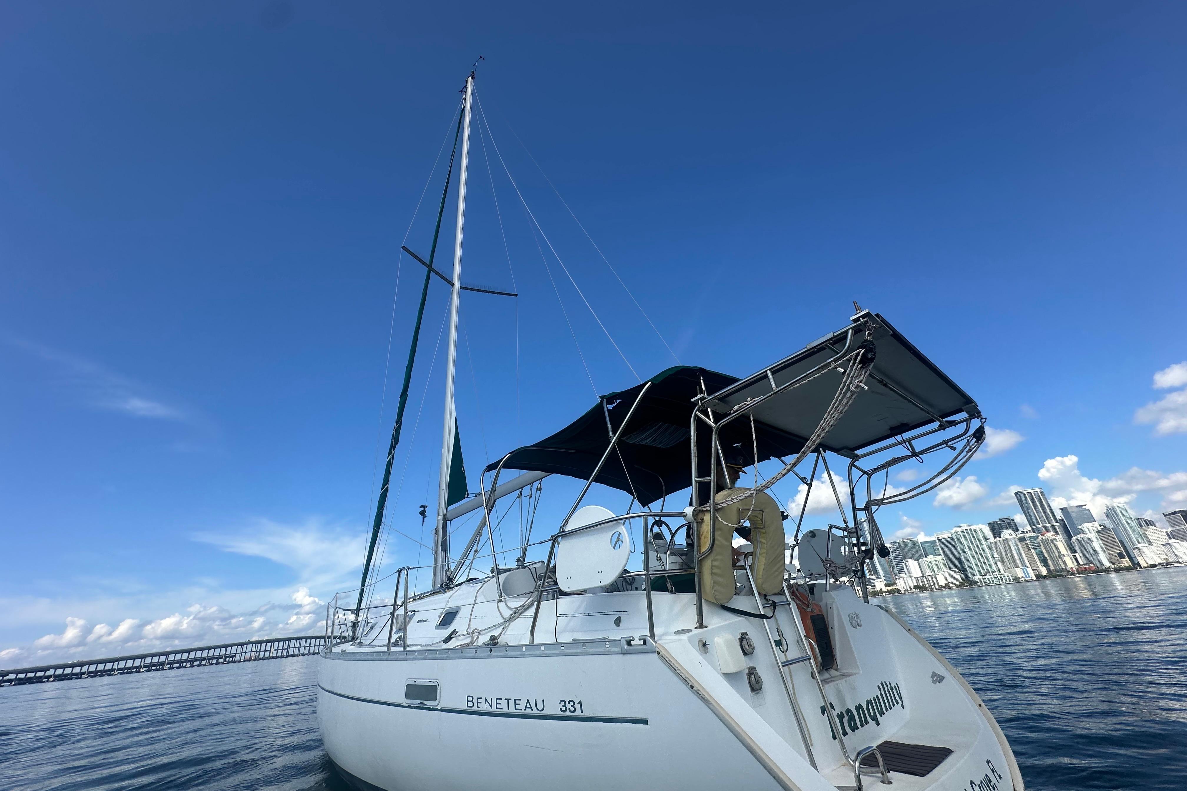 2003 Beneteau Oceanis Clipper 331 sailboat on calm water with city skyline backdrop.