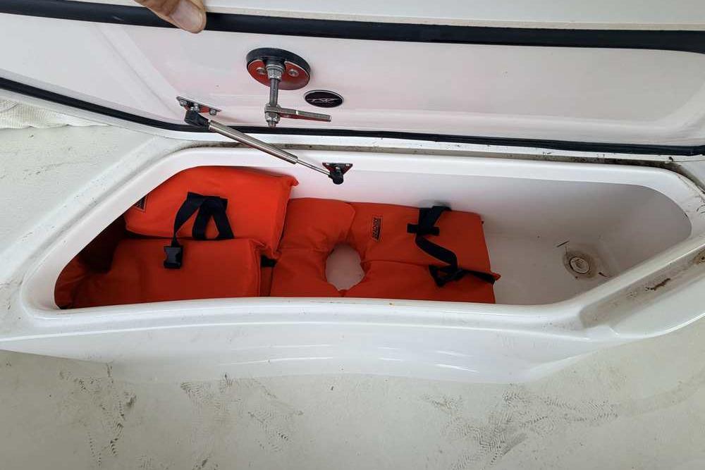 Storage compartment with orange life jackets on a 2024 Tidewater 232 LXF boat.