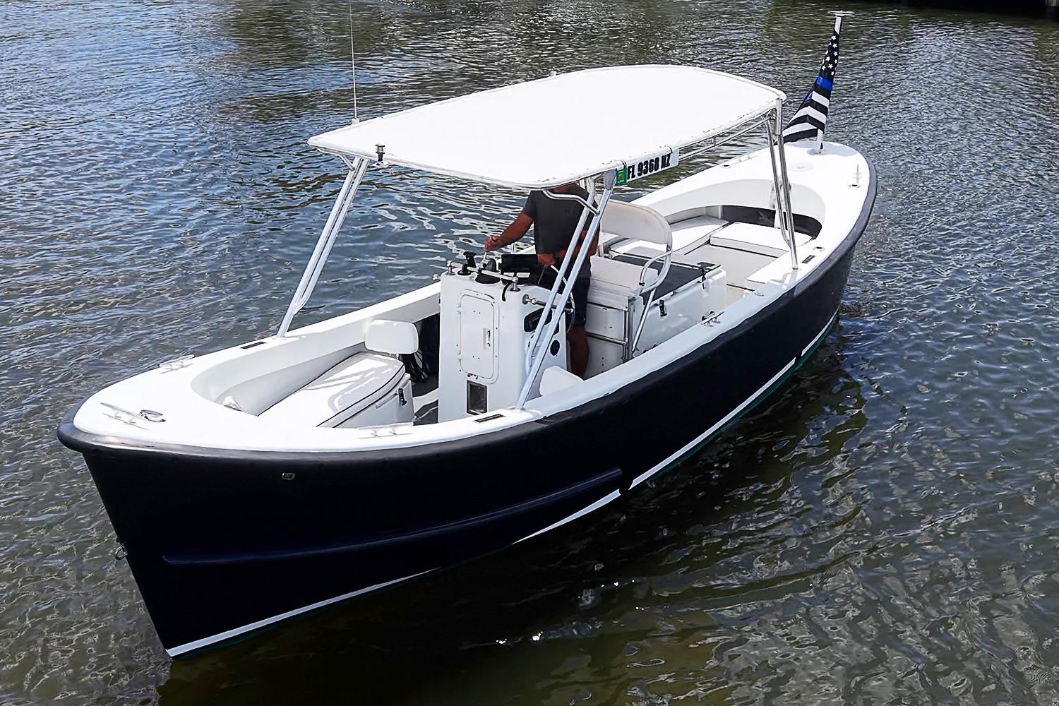 Custom 1969 boat with canopy cruising on calm water, featuring sleek design and American flag.
