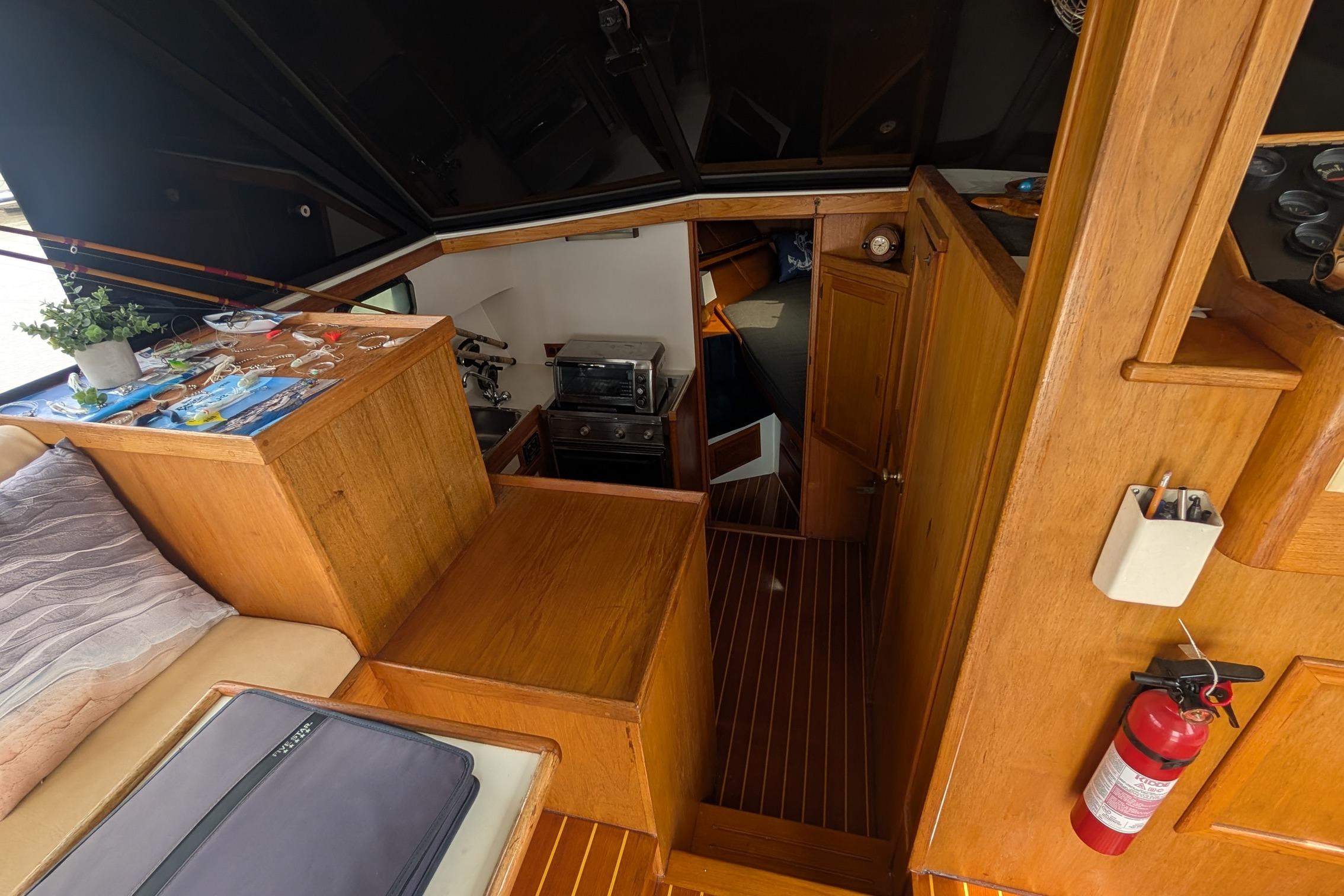 Interior of a 1987 Prowler 9M boat with wooden cabinetry and cozy seating area.