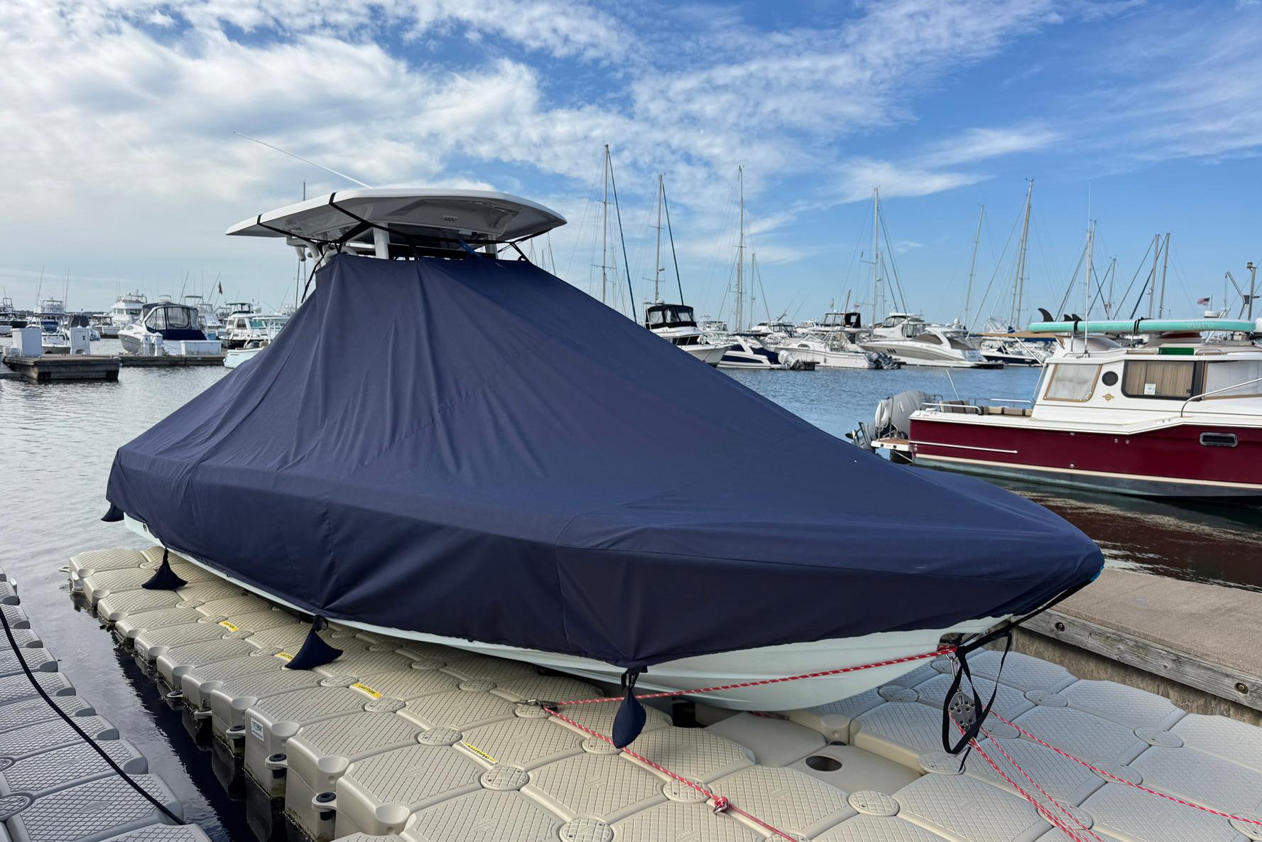 2021 Robalo 246 Cayman boat covered at marina dock with other boats in background.