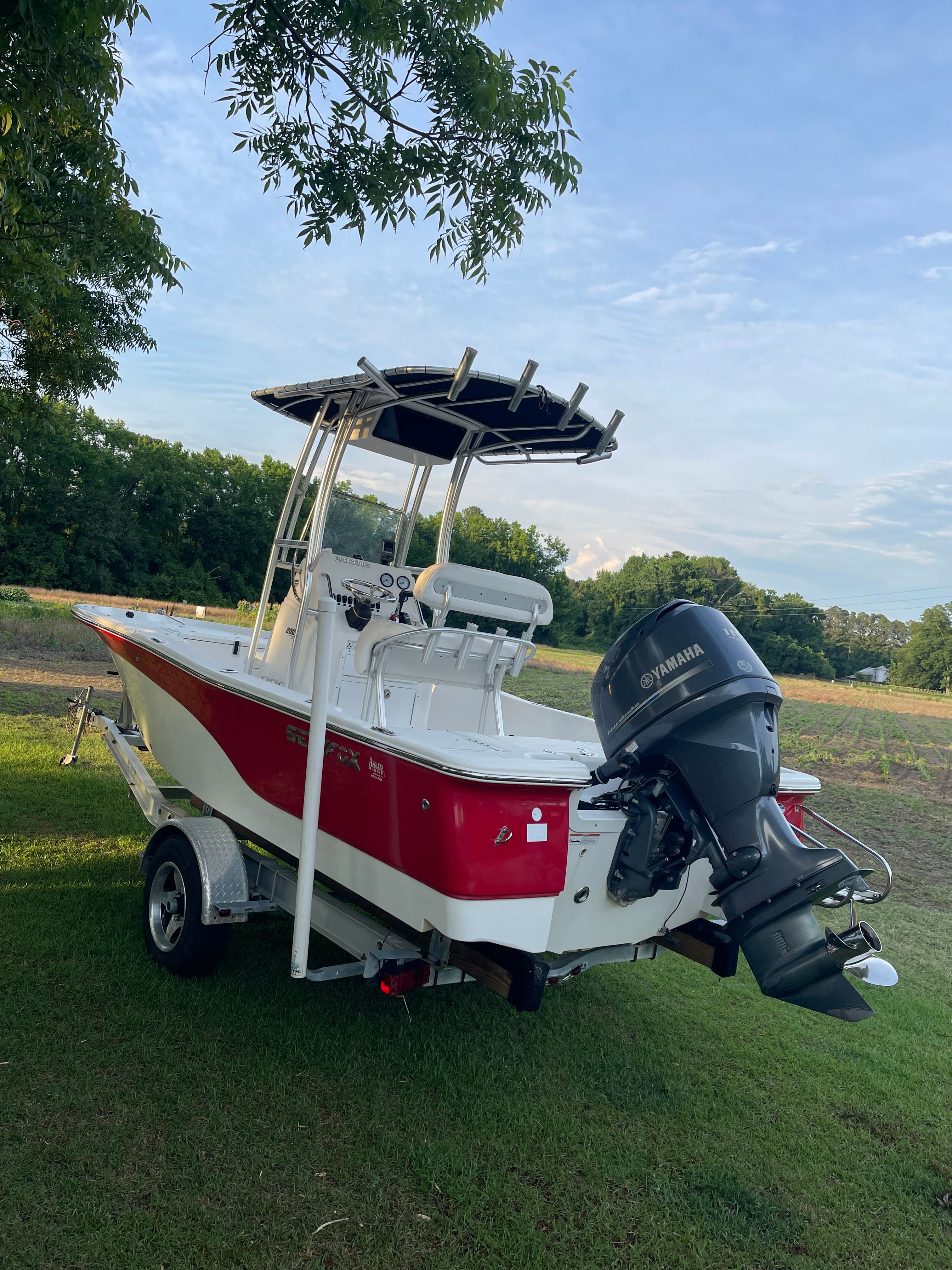 A 2012 Sea Fox 200XT boat on a trailer, parked on grass.