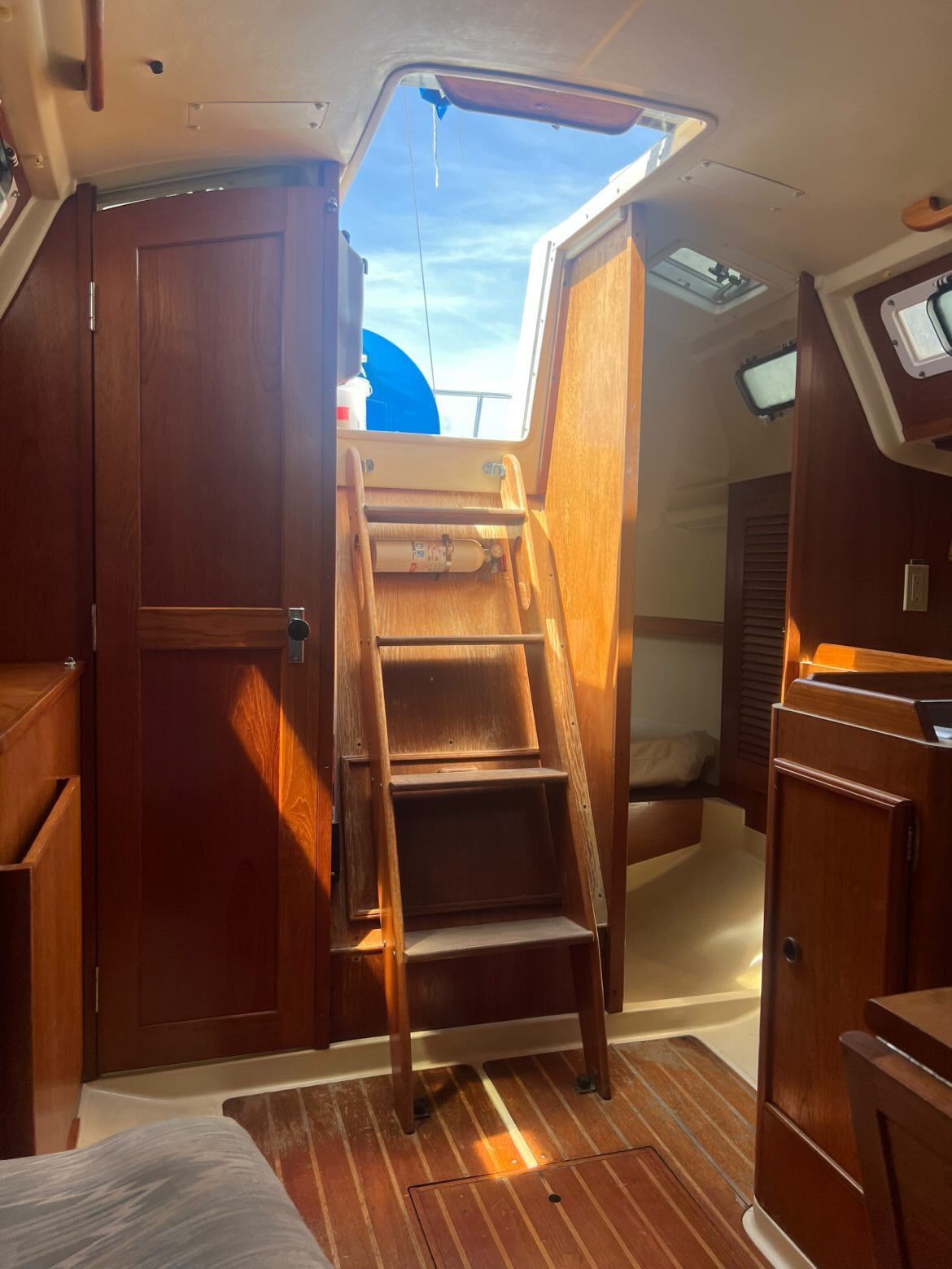Interior of a 1988 Pearson 28 sailboat with wooden stairs and cabinets.