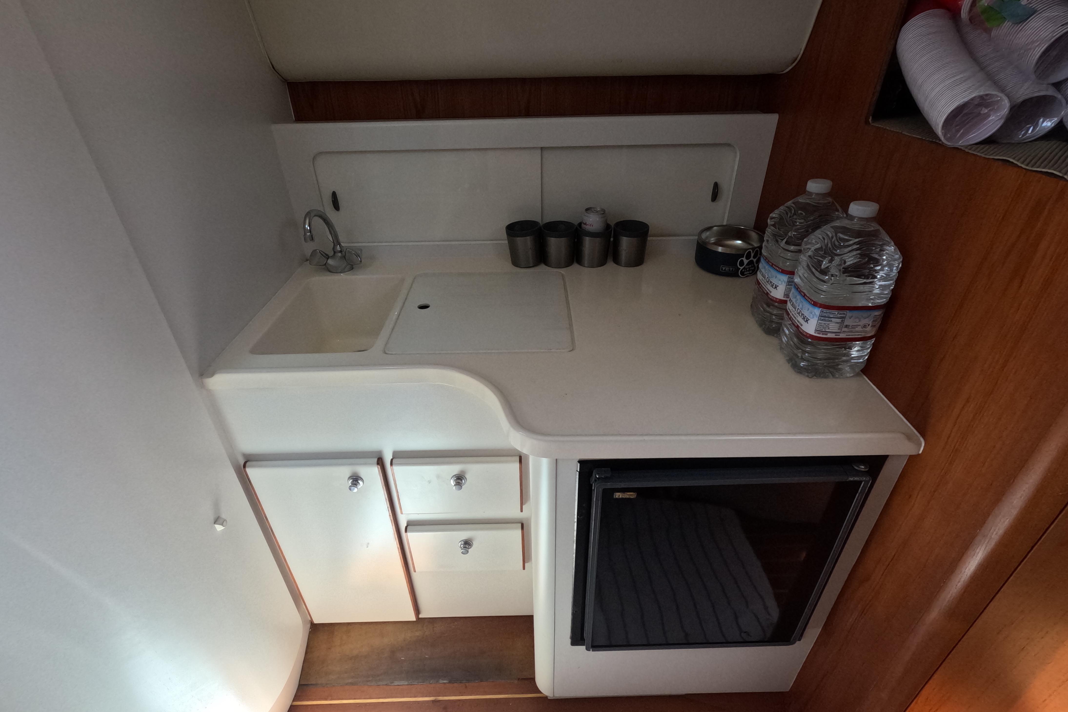 Compact galley in 1995 Tiara Yachts 2900 Open, featuring sink, storage, and mini-fridge.