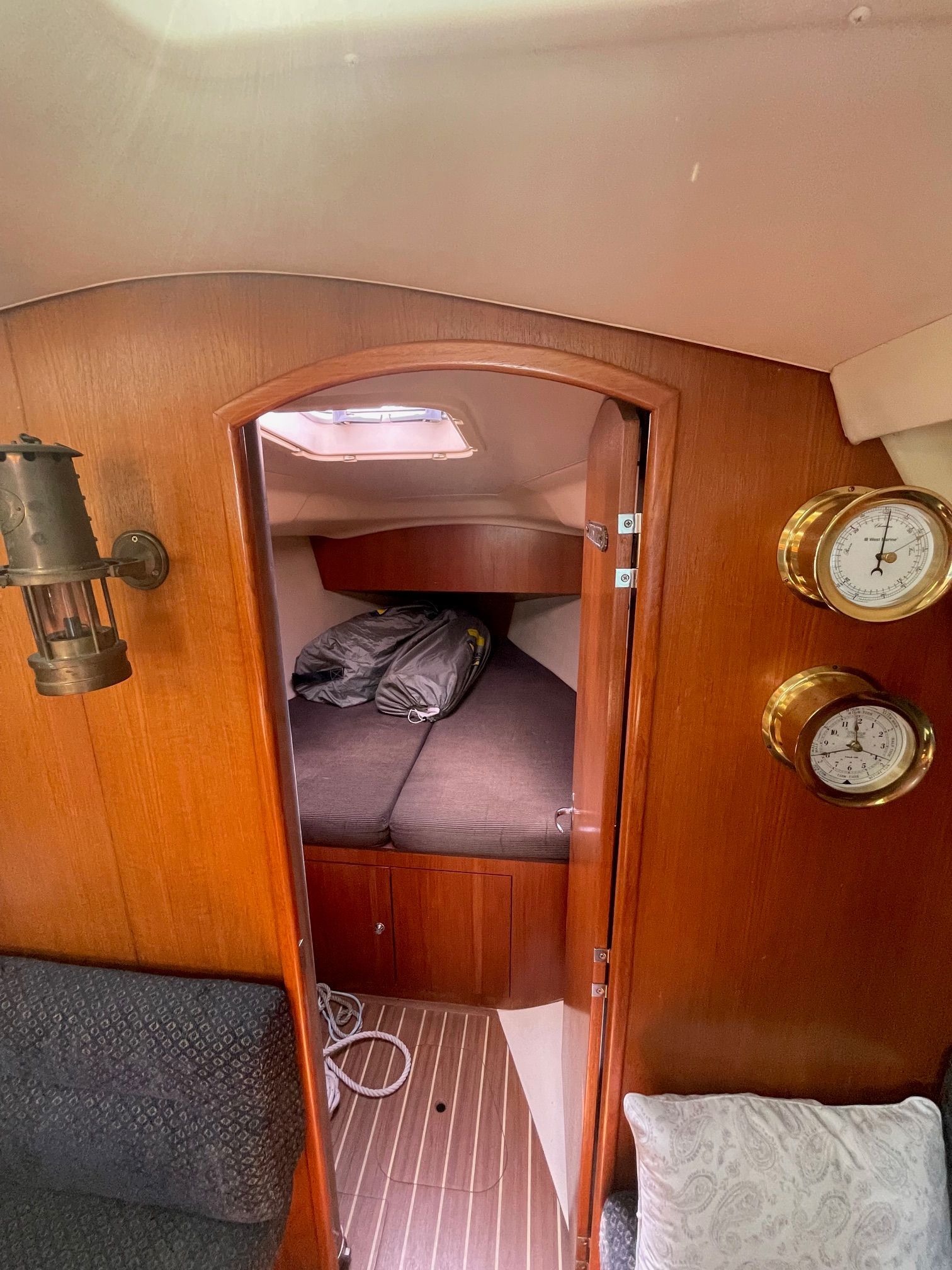 Interior of a sailboat with wooden walls, a bed, and nautical instruments.