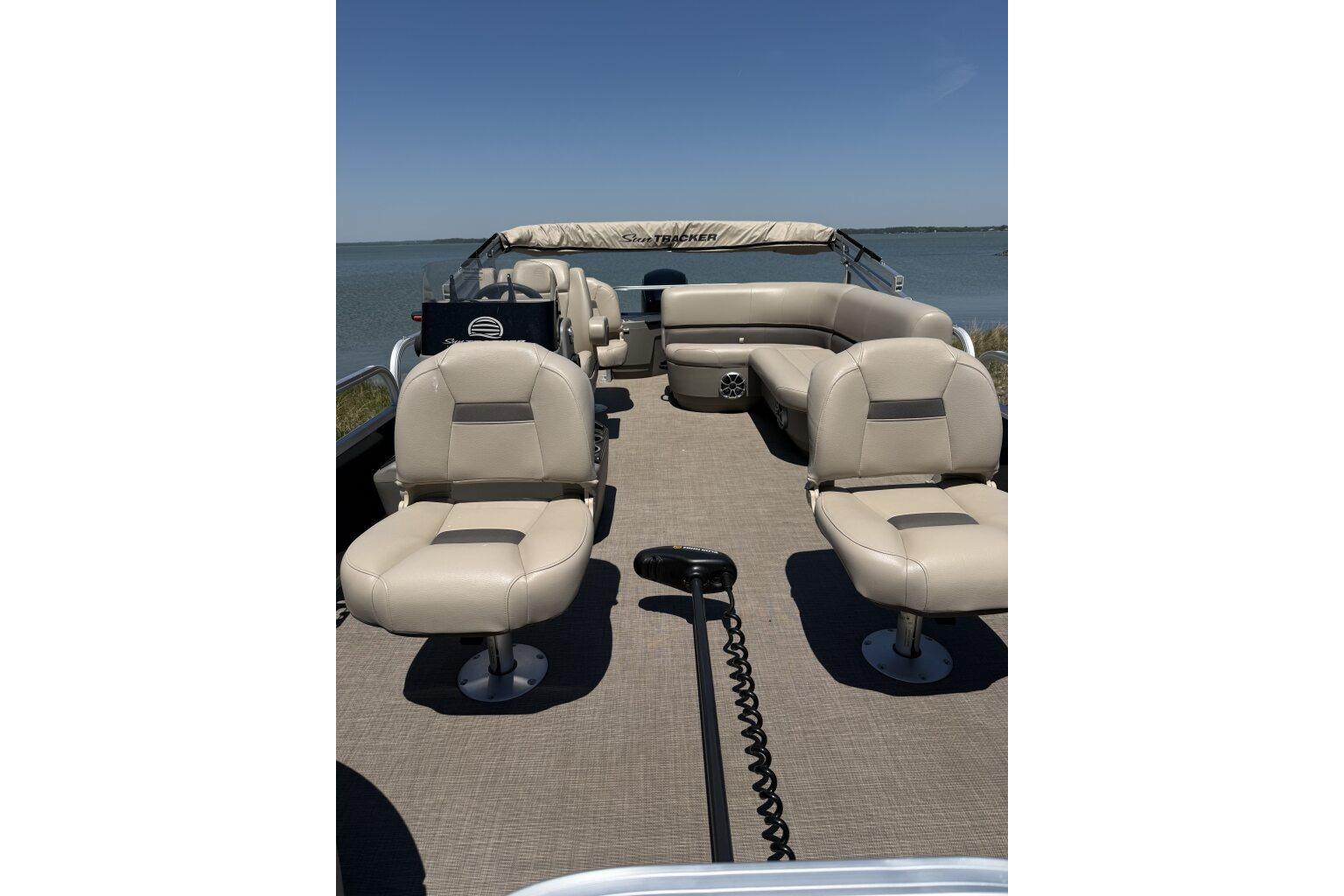 2024 Sun Tracker Bass Buggy 18 DLX pontoon boat with beige seating on a lake.