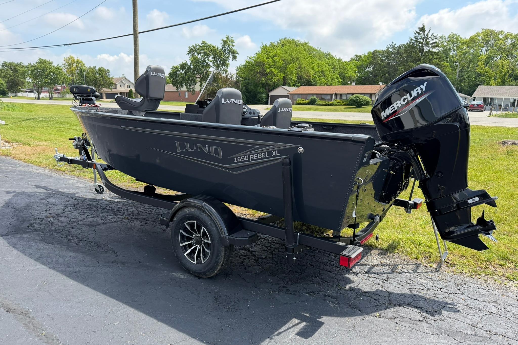 2027 Lund 1650 Rebel XL SS boat with Mercury engine on a trailer, parked outdoors.